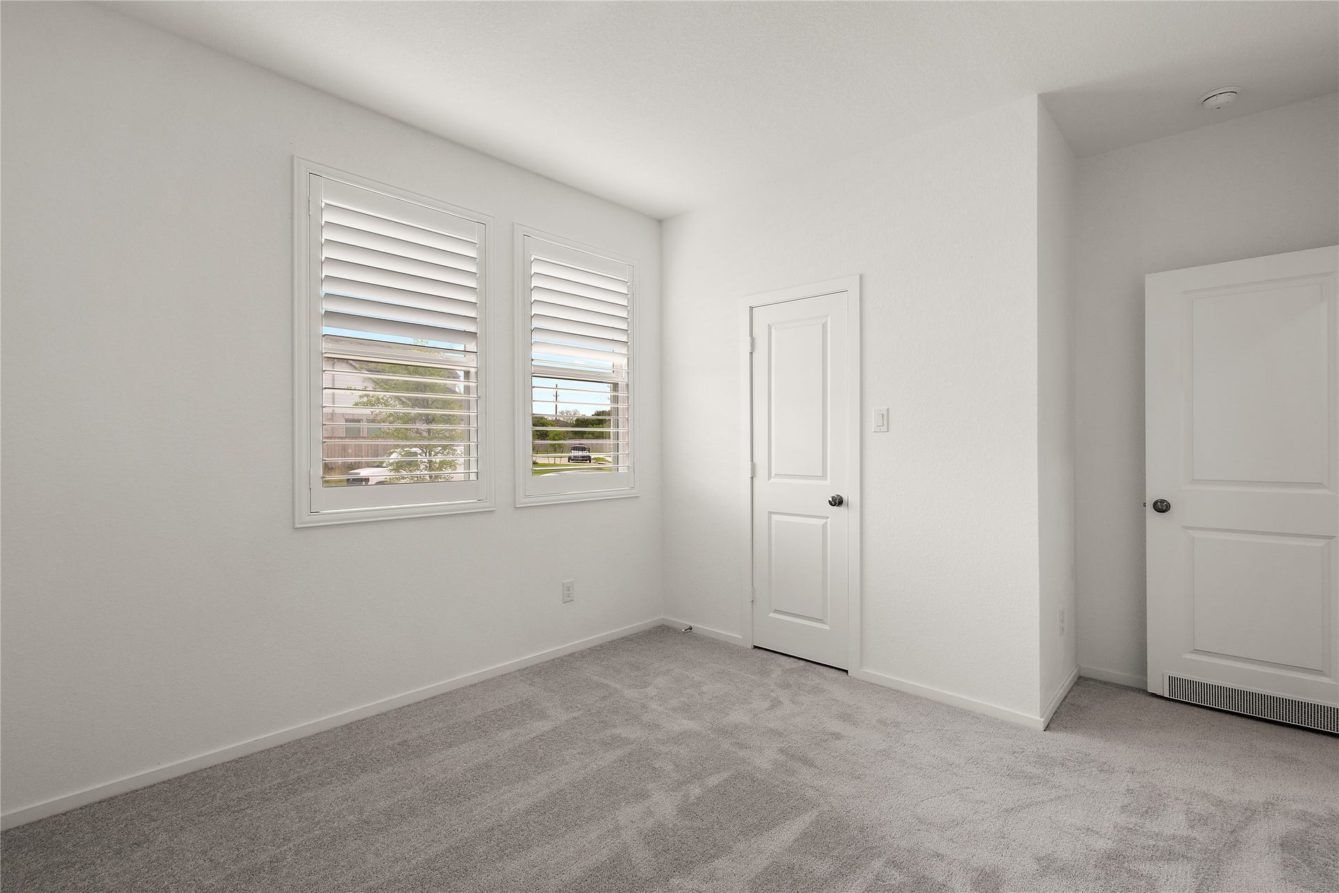 3414 Eden Valley Lane, Rosenberg, TX 77471 This room features soft gray carpeting, neutral white walls, and two windows with shutters, allowing natural light to brighten the space. It includes two doors, likely for a closet and entry, offering functionality and storage options.