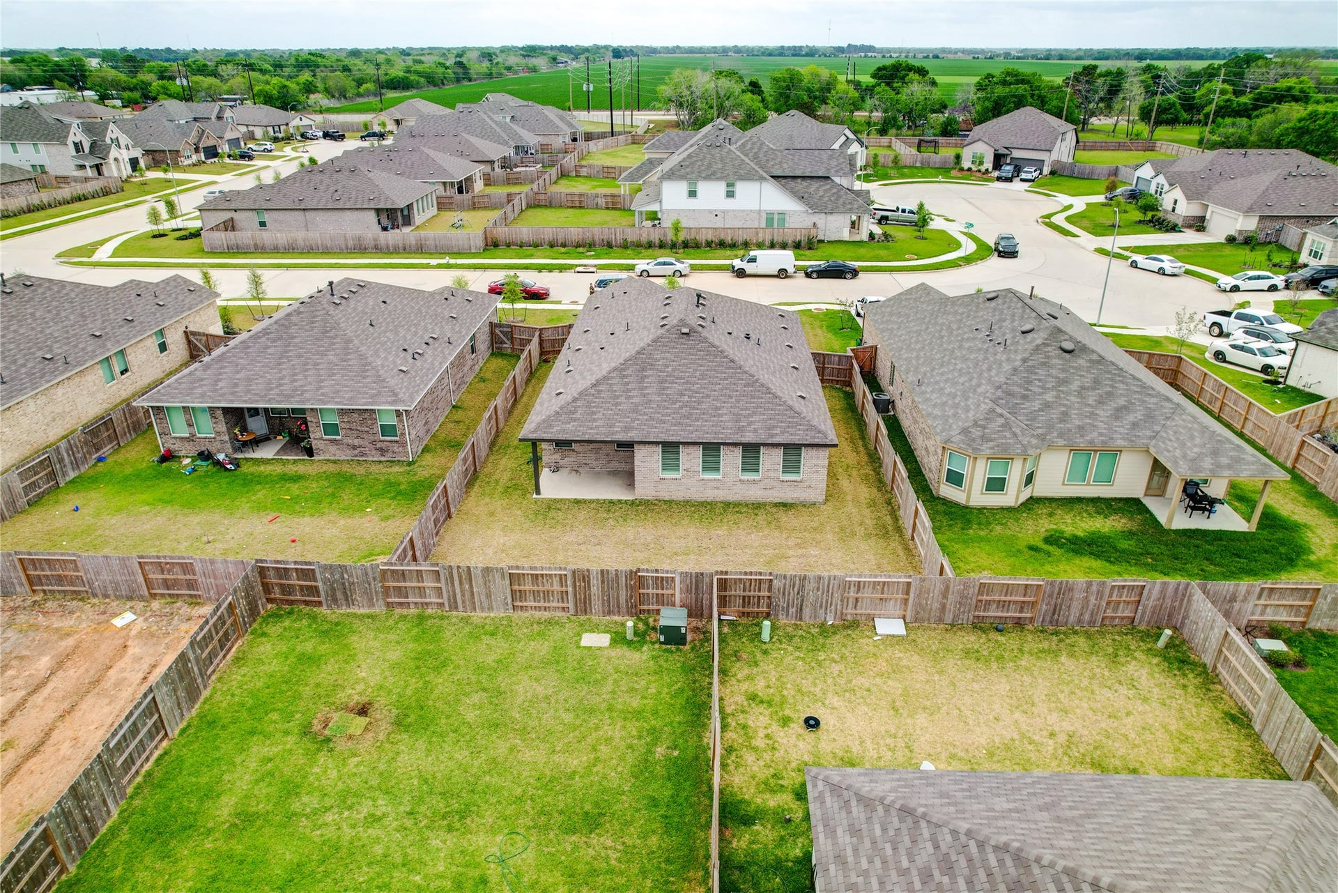 3414 Eden Valley Lane, Rosenberg, TX 77471 This aerial photo showcases a suburban neighborhood with neatly arranged single-story homes, each featuring fenced backyards. The area has wide streets, well-maintained lawns, and a peaceful atmosphere, ideal for a family-friendly community.