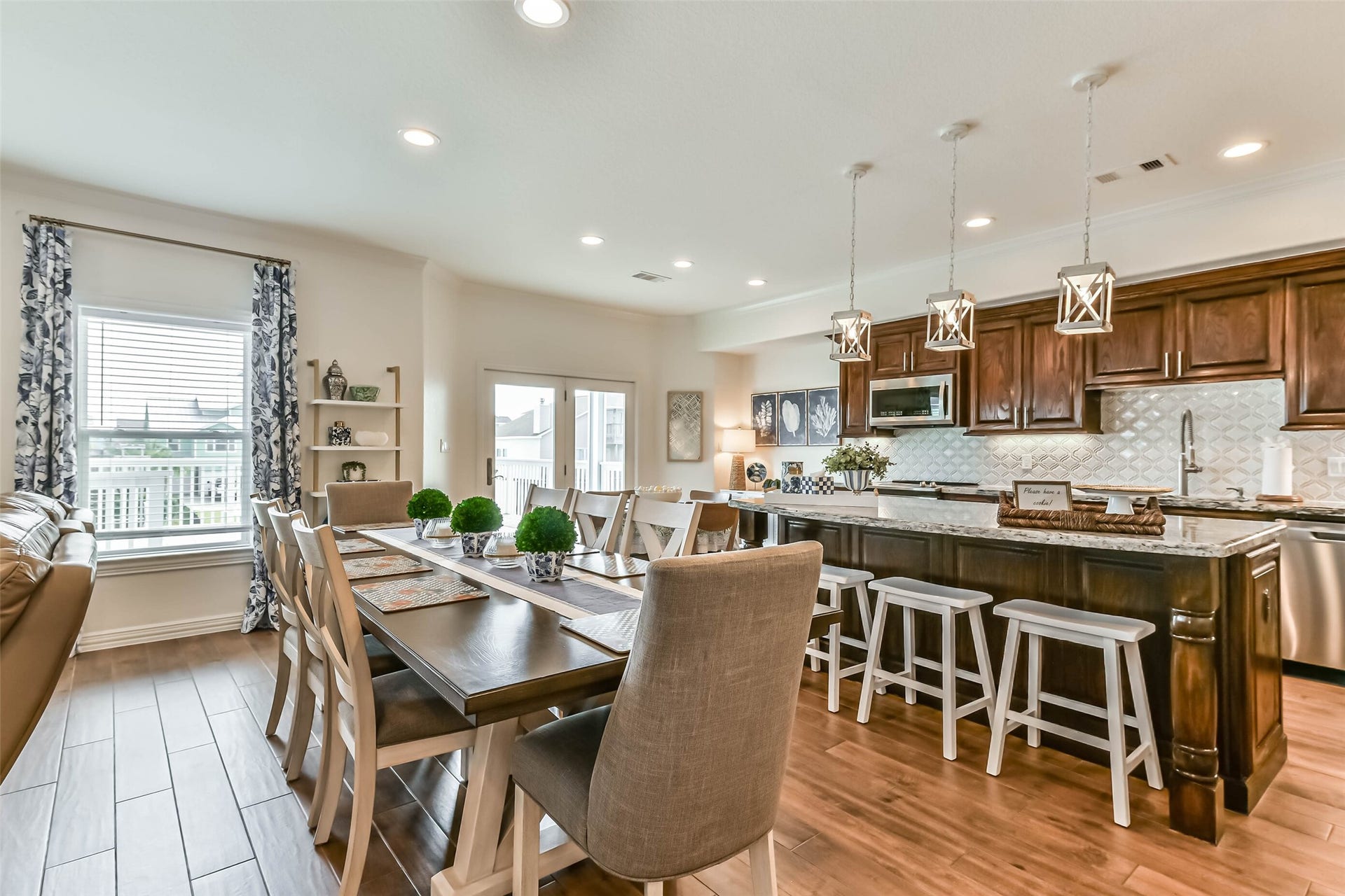 429 Jeanie Lynne Circle, Tiki Island, TX 77554 Beautifully styled open kitchen and dining area features coordinated furnishings, island bar seating, and designer lighting, all included with the home for a true turnkey experience.