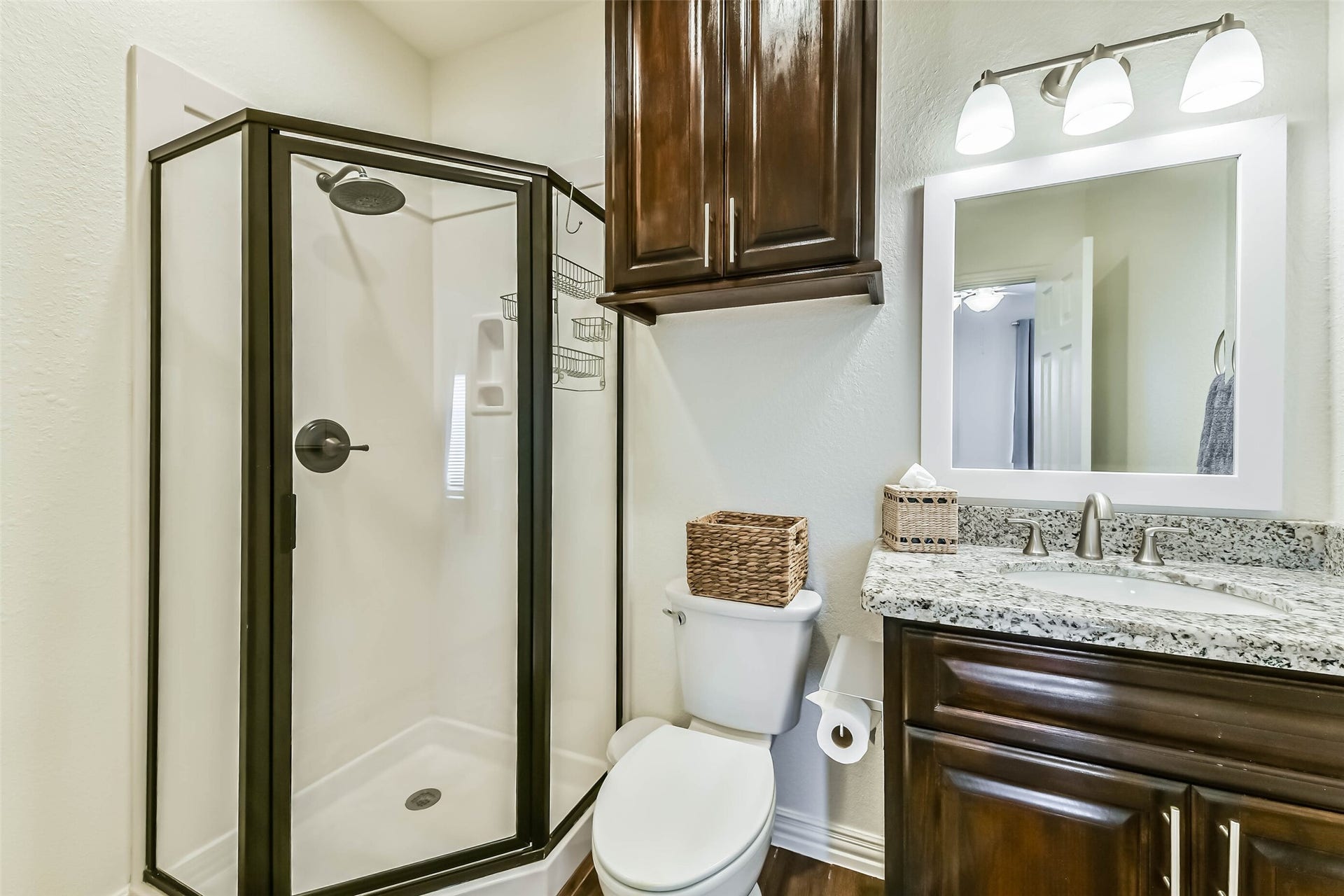 429 Jeanie Lynne Circle, Tiki Island, TX 77554 Bathroom features a glass-enclosed walk-in shower, granite vanity countertop, and overhead storage cabinetry.