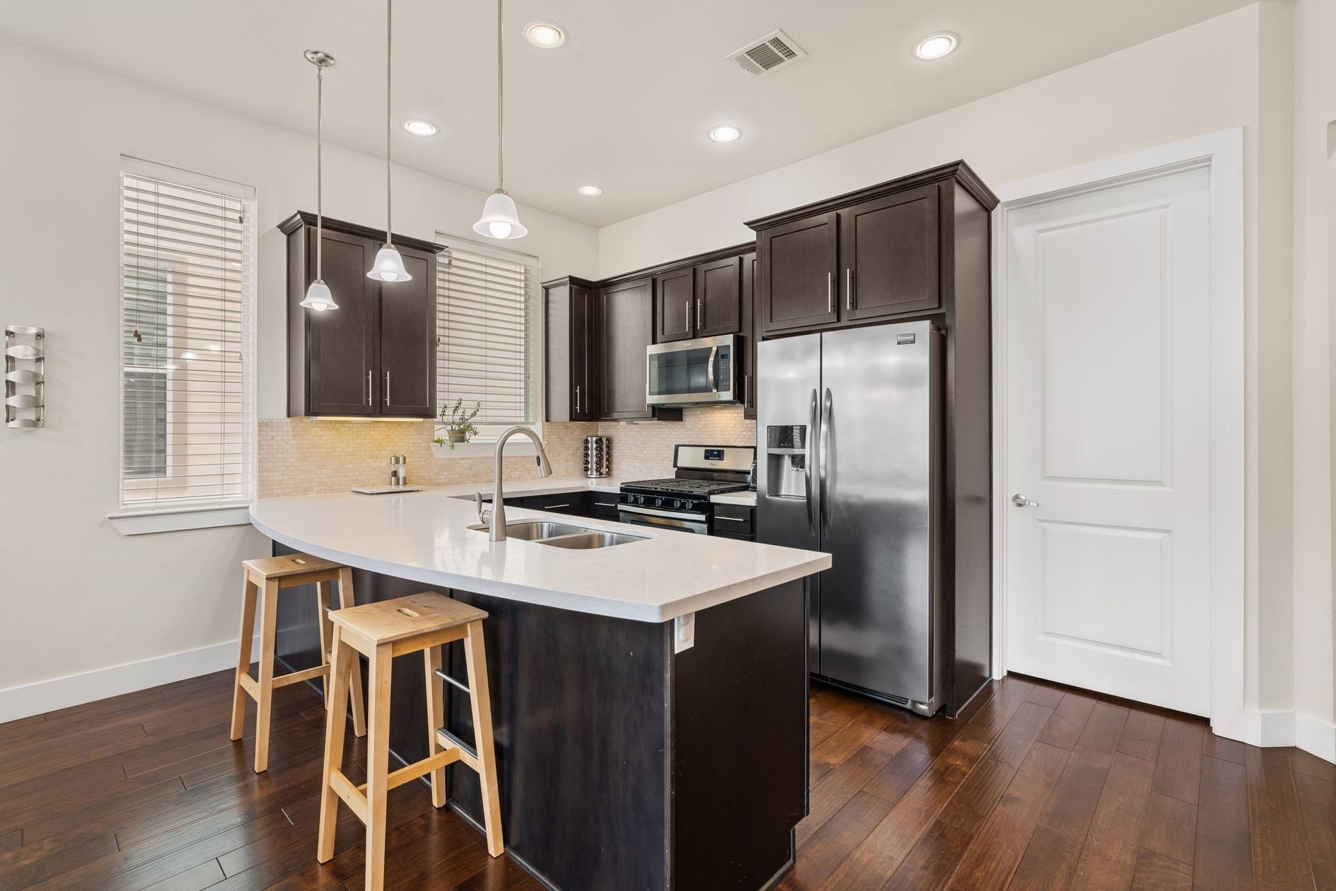 Here you'll find crisp quartz countertops, high-end stainless steel appliances, rich wood cabinetry, and an oversized breakfast bar perfect for casual mornings and evening conversations.