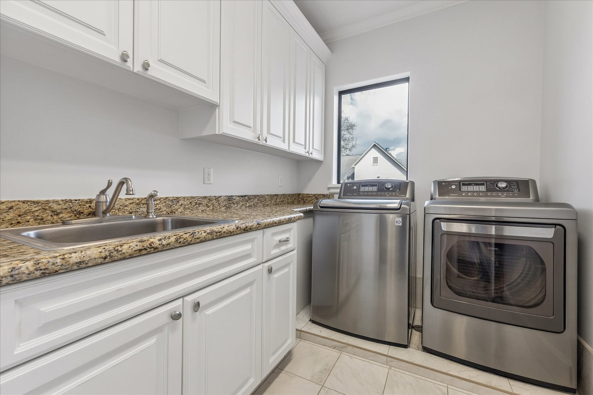 4022 Coleridge Street, West University Place, TX 77005 Functional laundry room with granite countertops, built-in cabinetry, utility sink, and stainless washer and dryer.