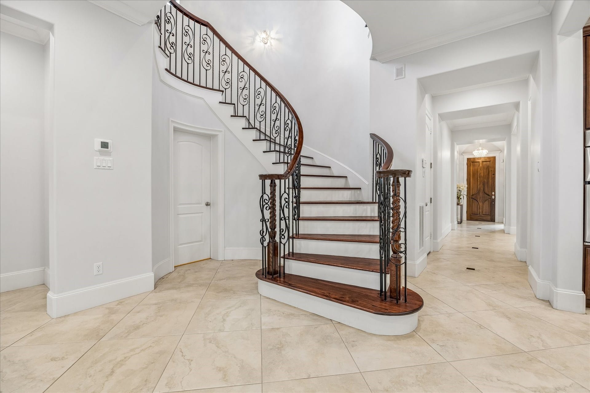 4022 Coleridge Street, West University Place, TX 77005 Dramatic entry foyer featuring soaring ceilings, a sweeping curved staircase with wrought-iron balusters, and oversized stone flooring.