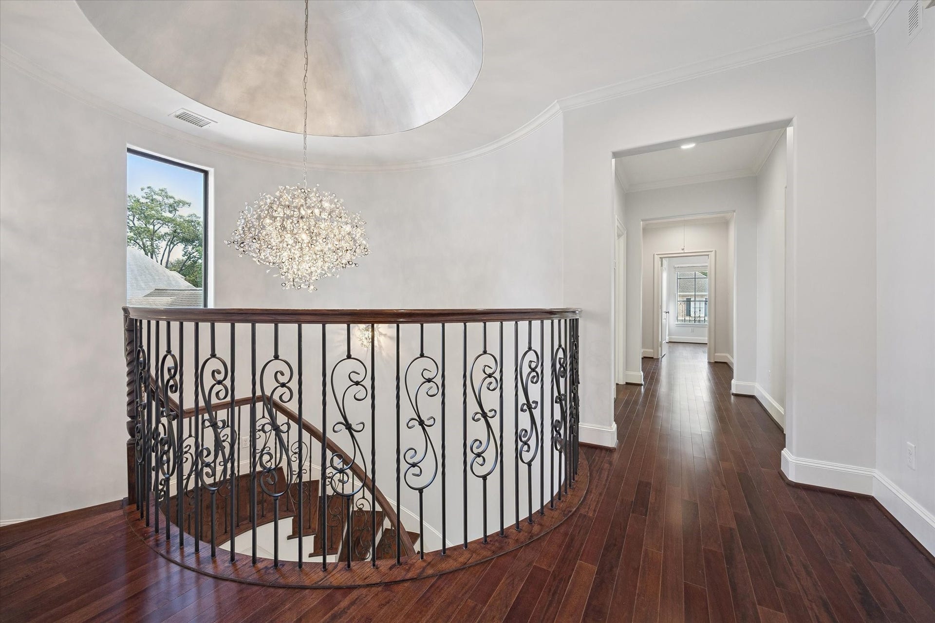4022 Coleridge Street, West University Place, TX 77005 Elegant second-floor landing overlooking the grand staircase with decorative wrought-iron railing and a striking designer chandelier beneath a domed ceiling.