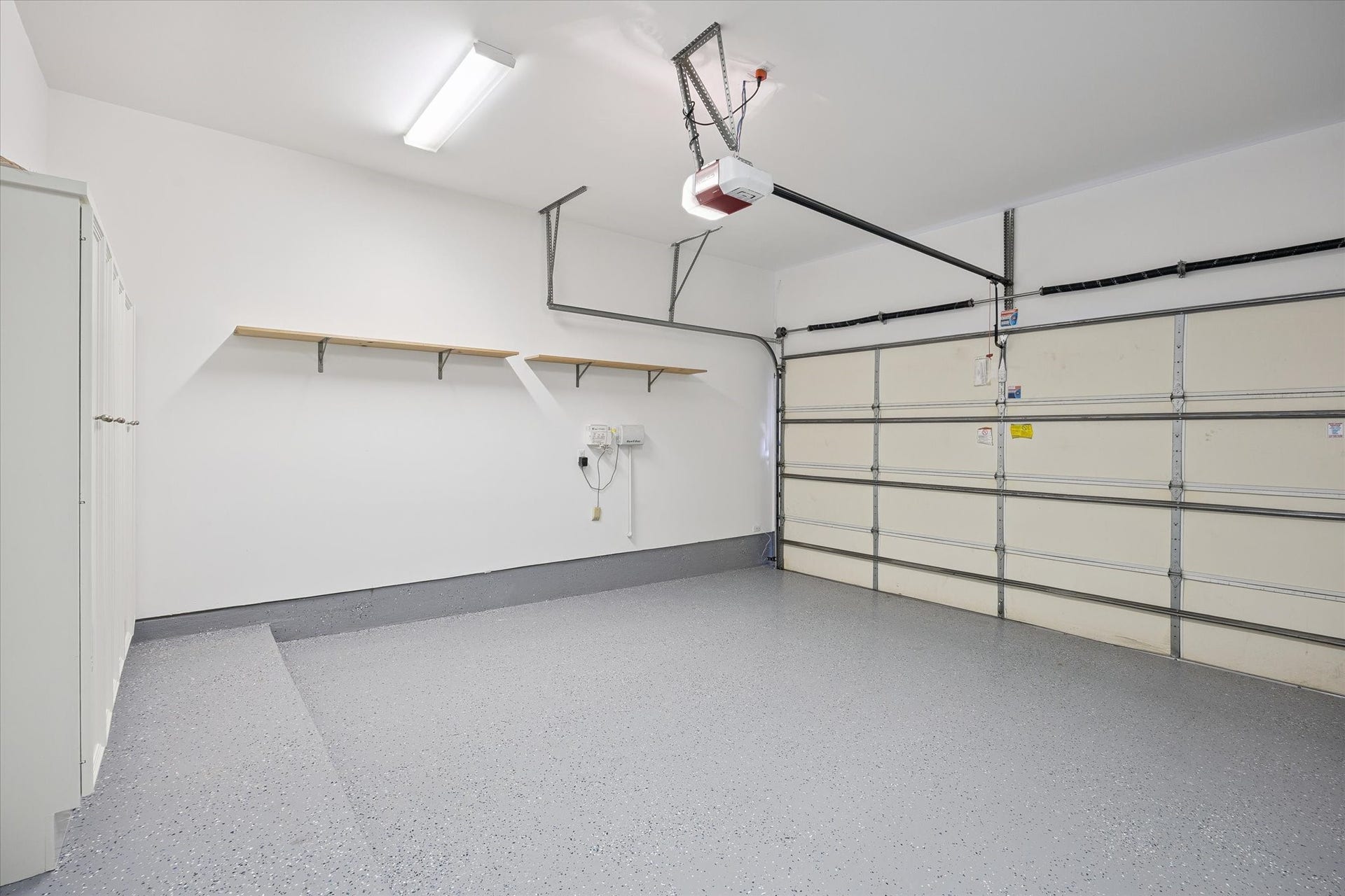 4022 Coleridge Street, West University Place, TX 77005 Large two-car garage with an 11-foot ceiling, fresh paint, and recent epoxy flooring, featuring abundant storage with open shelving, built-in cabinets, and a spacious closet.