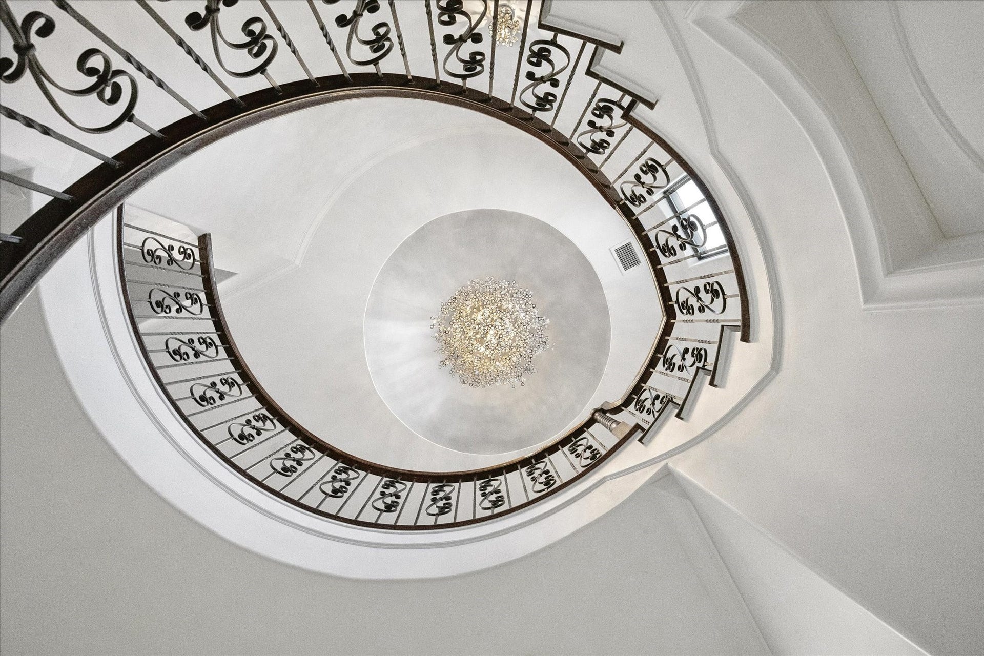 4022 Coleridge Street, West University Place, TX 77005 Dramatic view of the gracefully curved wrought-iron staircase beneath a domed ceiling crowned by a dazzling designer chandelier.