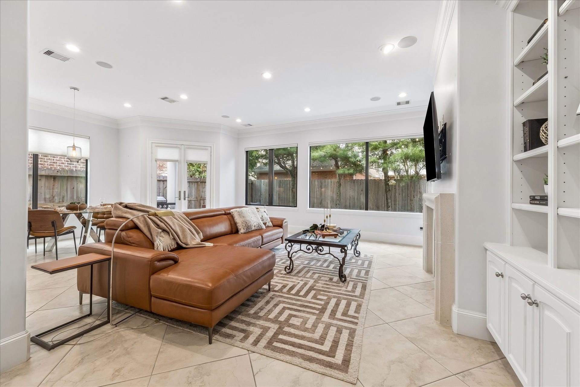 4022 Coleridge Street, West University Place, TX 77005 Spacious family room with built-in cabinetry, gas log fireplace, surround sound speakers, and large bay windows overlooking the backyard.