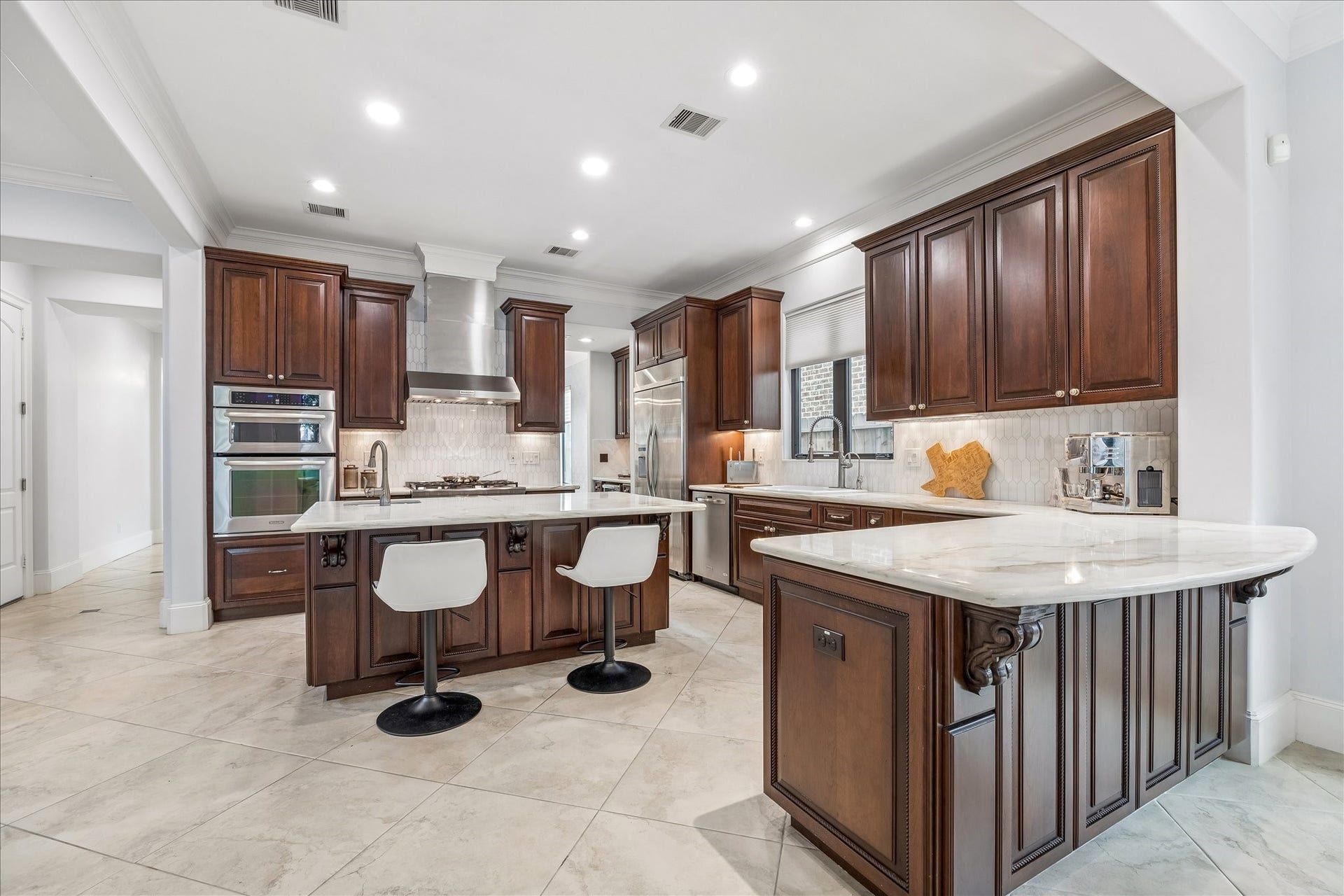 4022 Coleridge Street, West University Place, TX 77005 Chefs kitchen with marble countertops, custom cabinetry, professional-grade stainless appliances, and oversized island seating.