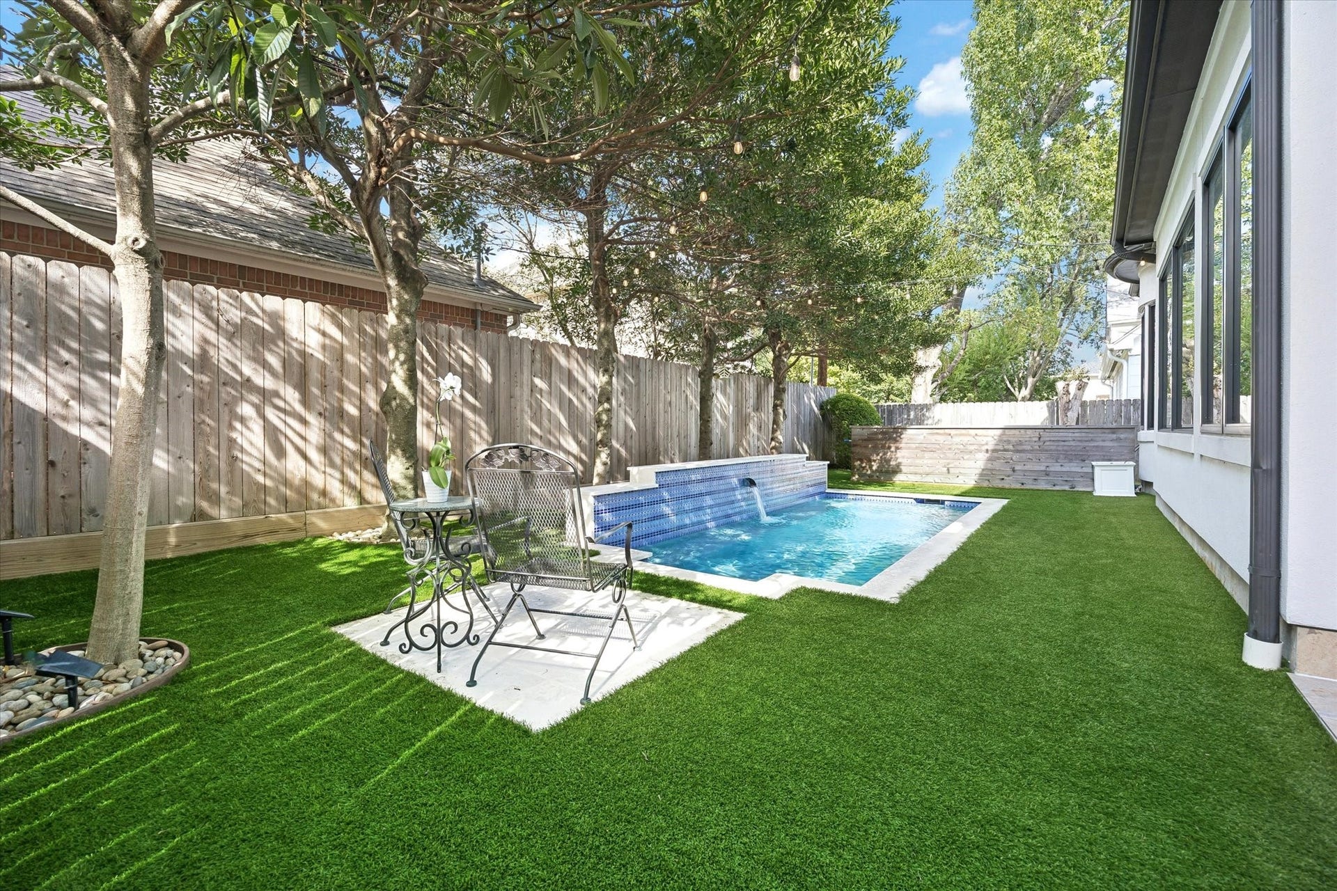 4022 Coleridge Street, West University Place, TX 77005 Private backyard retreat featuring a sparkling pool with water feature, low-maintenance turf, mature trees, and patio seating.