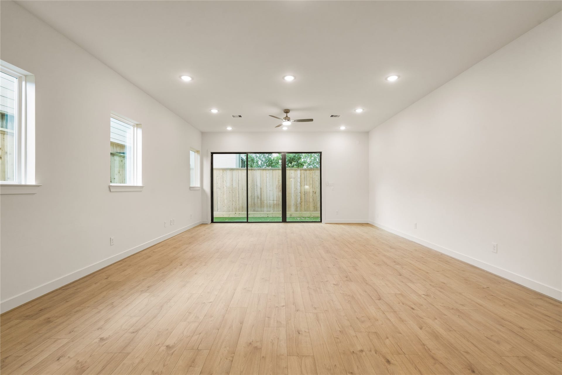 5016 Schuler Street, Houston, TX 77007 Spacious main living hall wall-to-wall oak-look flooring, recessed LED lighting throughout, side-yard accent windows, and oversized glass sliding doors opening to the backyard.