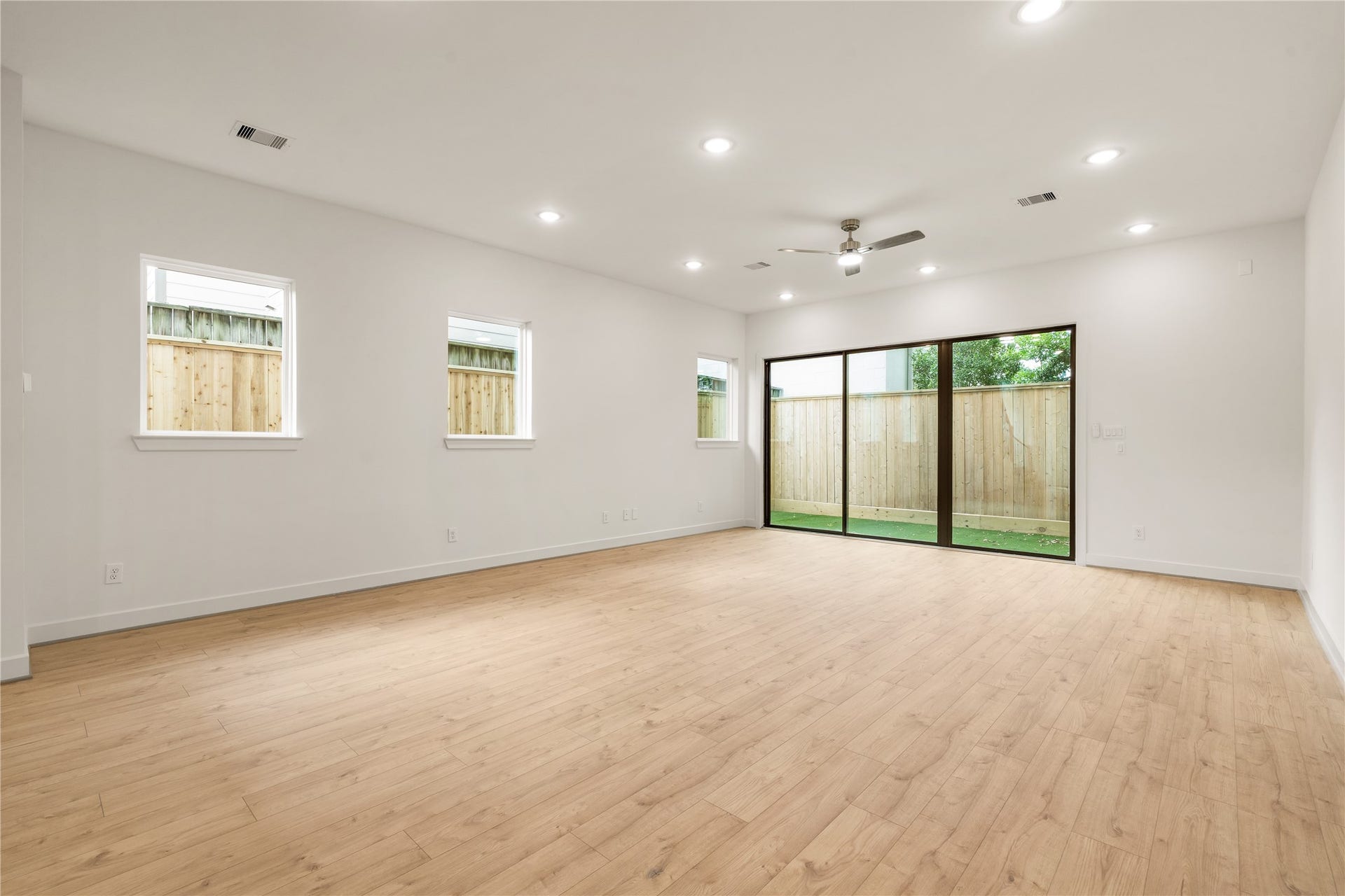 5016 Schuler Street, Houston, TX 77007 Expansive open living space continuous oak-look flooring, multiple side windows providing balanced natural light, and modern ceiling fan detail.