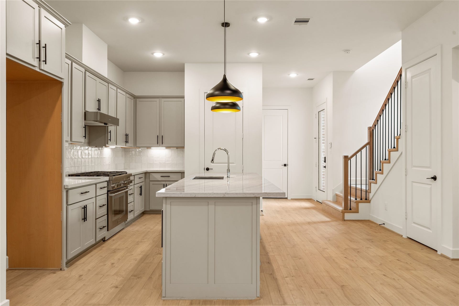 5016 Schuler Street, Houston, TX 77007 Heart of the main level centered island prep station, wide-plank oak flooring, and direct sightlines to the stair run and entry foyer.