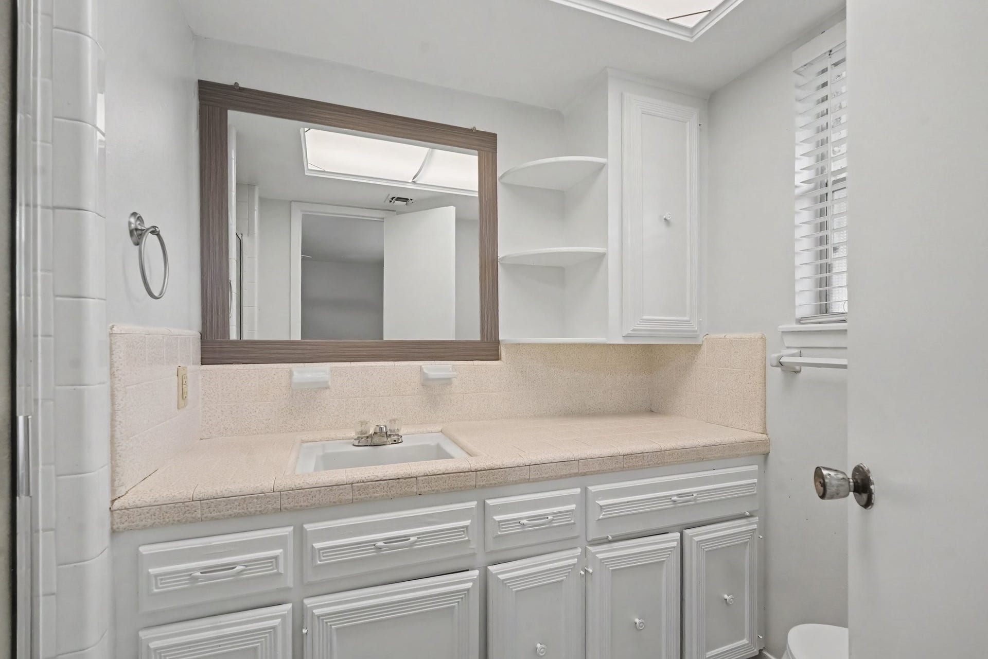 429 Deep Dale Lane, Conroe, TX 77304 This ensuite bath is light and bright, featuring ample storage with built-in drawers and cabinets, convenient corner shelving, and a charming window that allows for plenty of natural light.