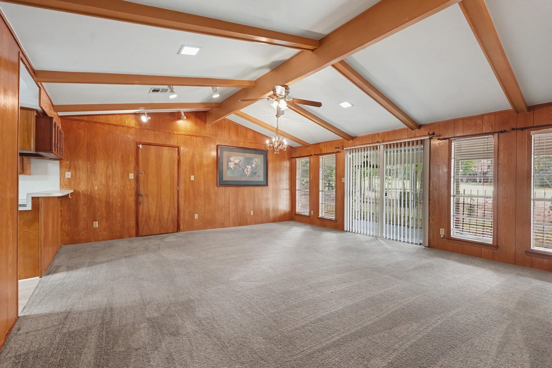 429 Deep Dale Lane, Conroe, TX 77304 Spacious family room featuring vaulted beamed ceilings, a wall of oversized windows with scenic views, and seamless outdoor access through sliding glass doors. This inviting space is finished with comfortable carpeting throughout, making it an ideal setting for both relaxing with family and hosting guests.
