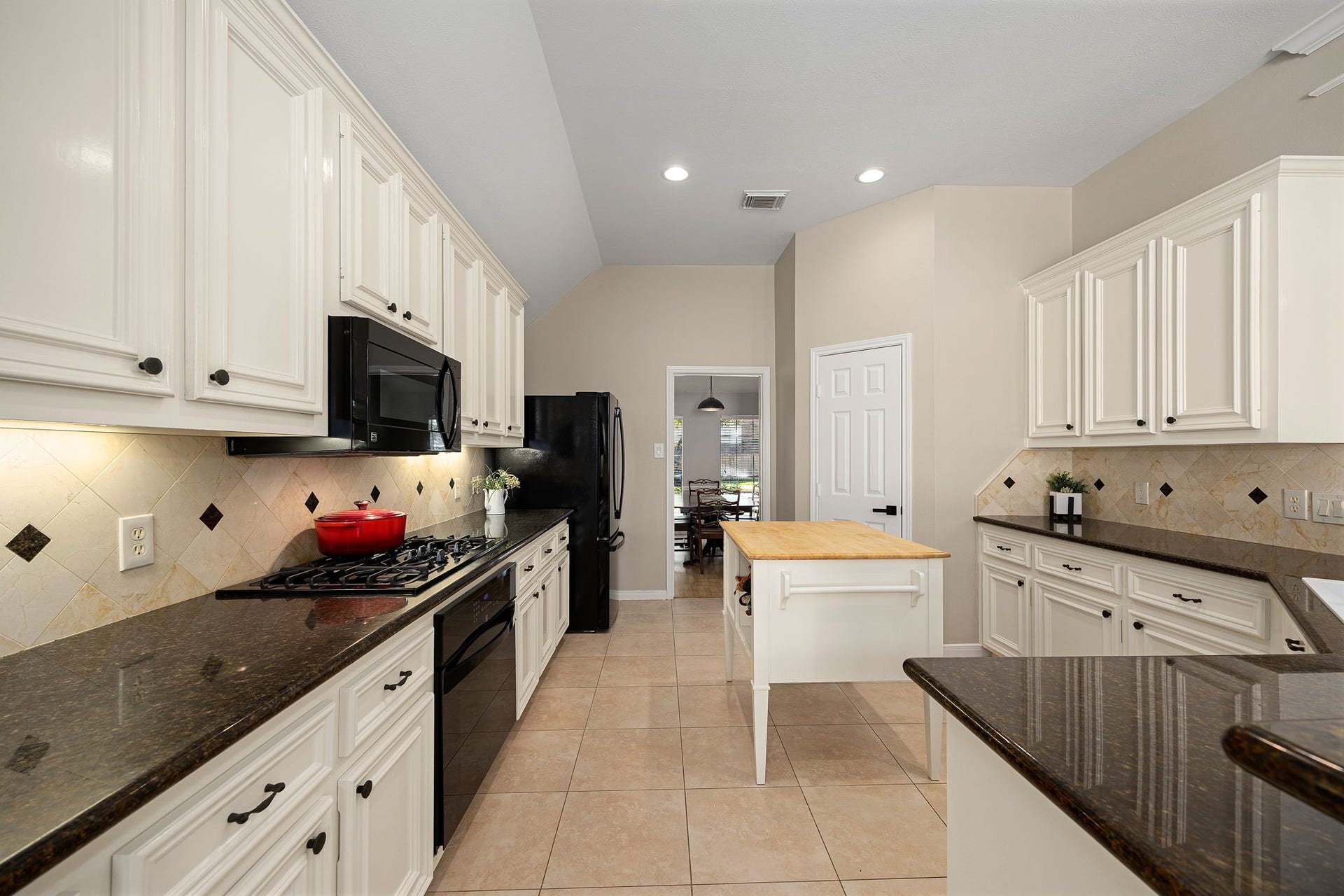 8327 E Copper Village Drive, Houston, TX 77095 A gas cooktop, tiled backsplash, and under-cabinet lighting make this galley-style kitchen both functional and stylish.