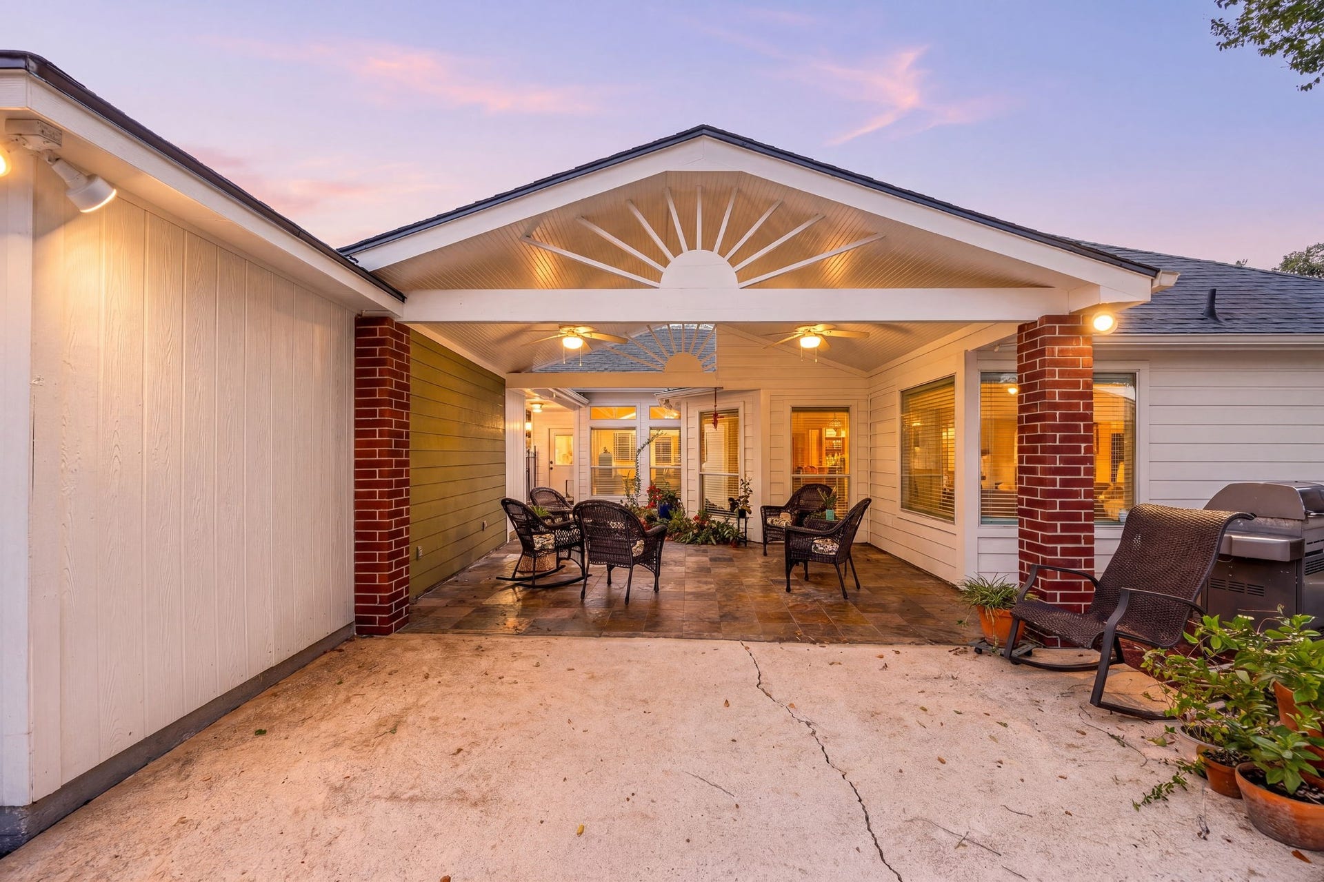 8327 E Copper Village Drive, Houston, TX 77095 As evening falls, the covered patio glows beautifully, showcasing the tiled flooring, brick columns, and the additional concrete slab extending the outdoor living space.
