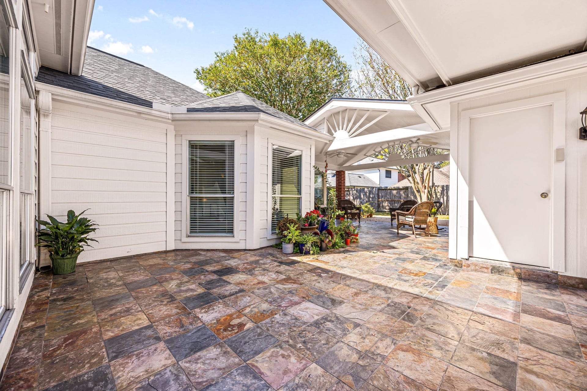8327 E Copper Village Drive, Houston, TX 77095 The covered back patio features a beautiful tiled floor and a charming sunburst gable detail, creating a warm, inviting space to relax outdoors.