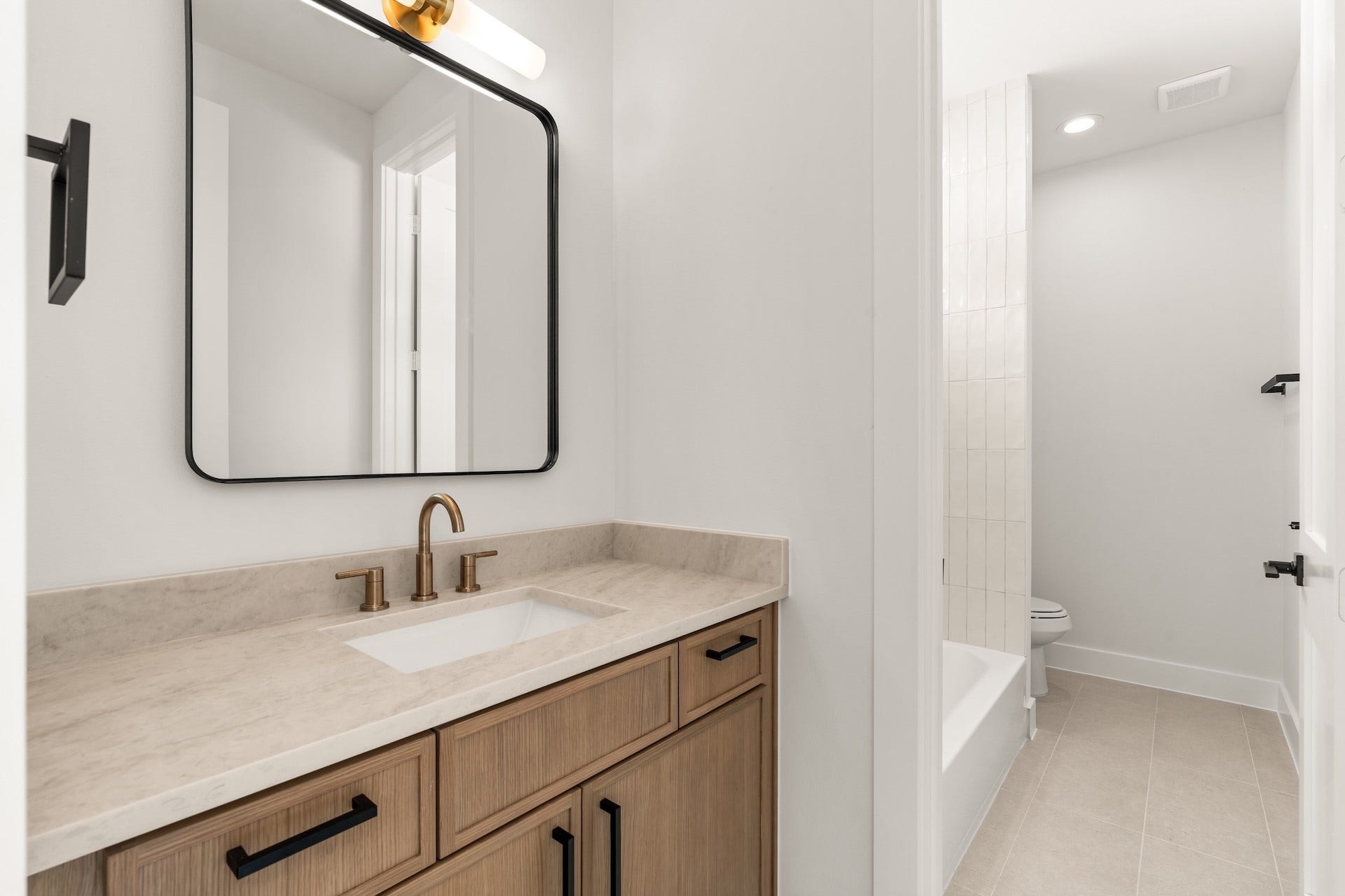 Modern jack and jill hall bath featuring a stylish vanity layout and tub/shower combination.