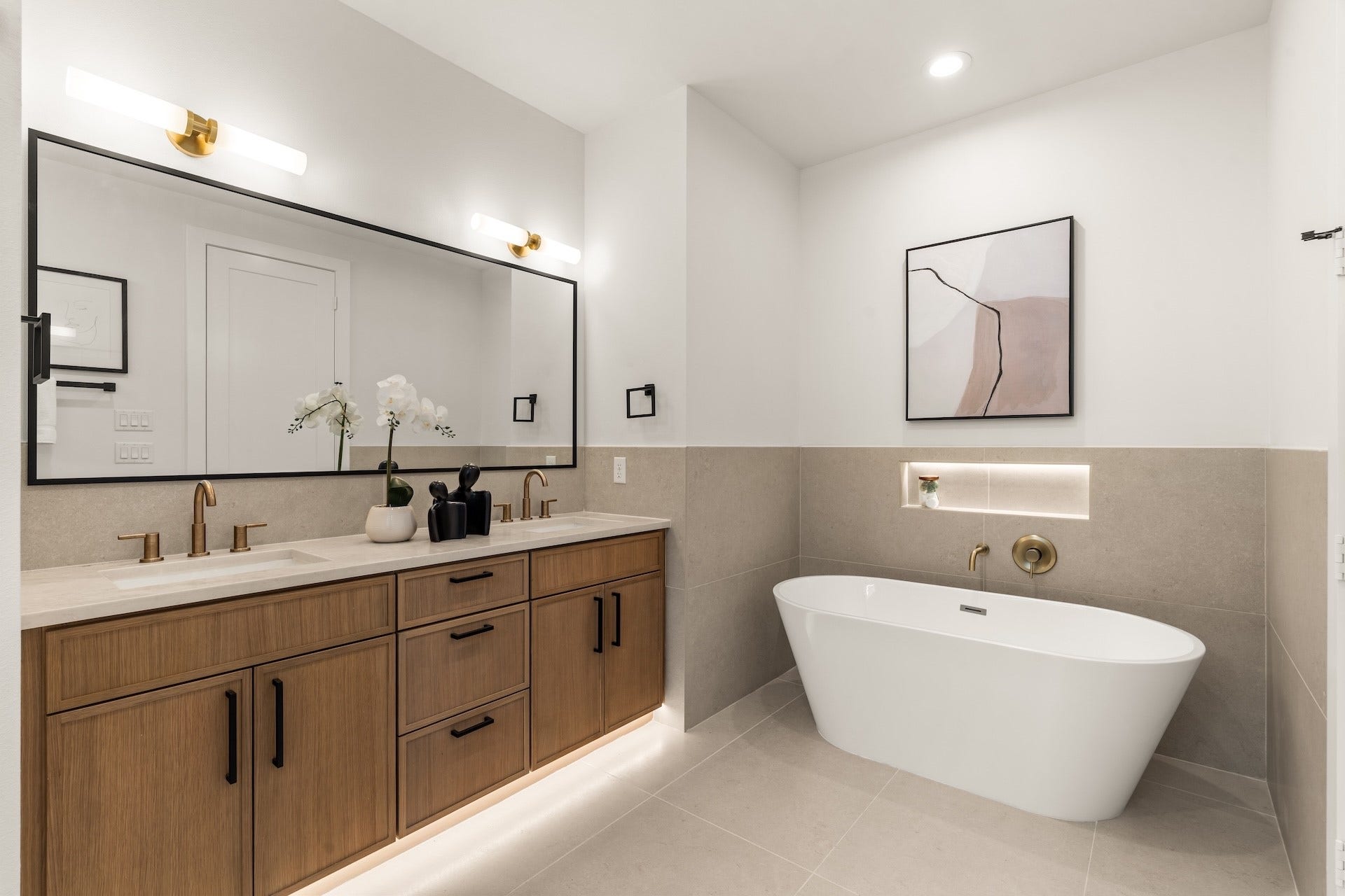 Spa-inspired primary ensuite featuring a deep freestanding soaking tub, dual vanity, and ambient accent lighting.