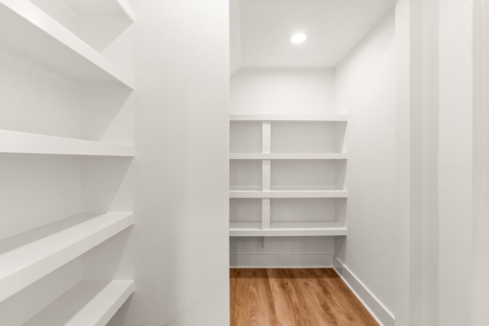 Dedicated walk-in pantry equipped with custom built-in shelving for optimal kitchen organization.
