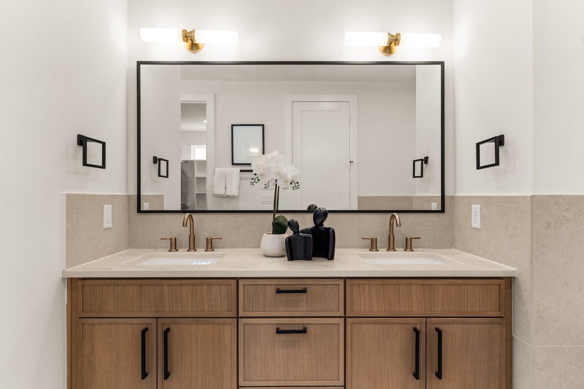 Dual undermount vanity station equipped with warm brass hardware and abundant storage.