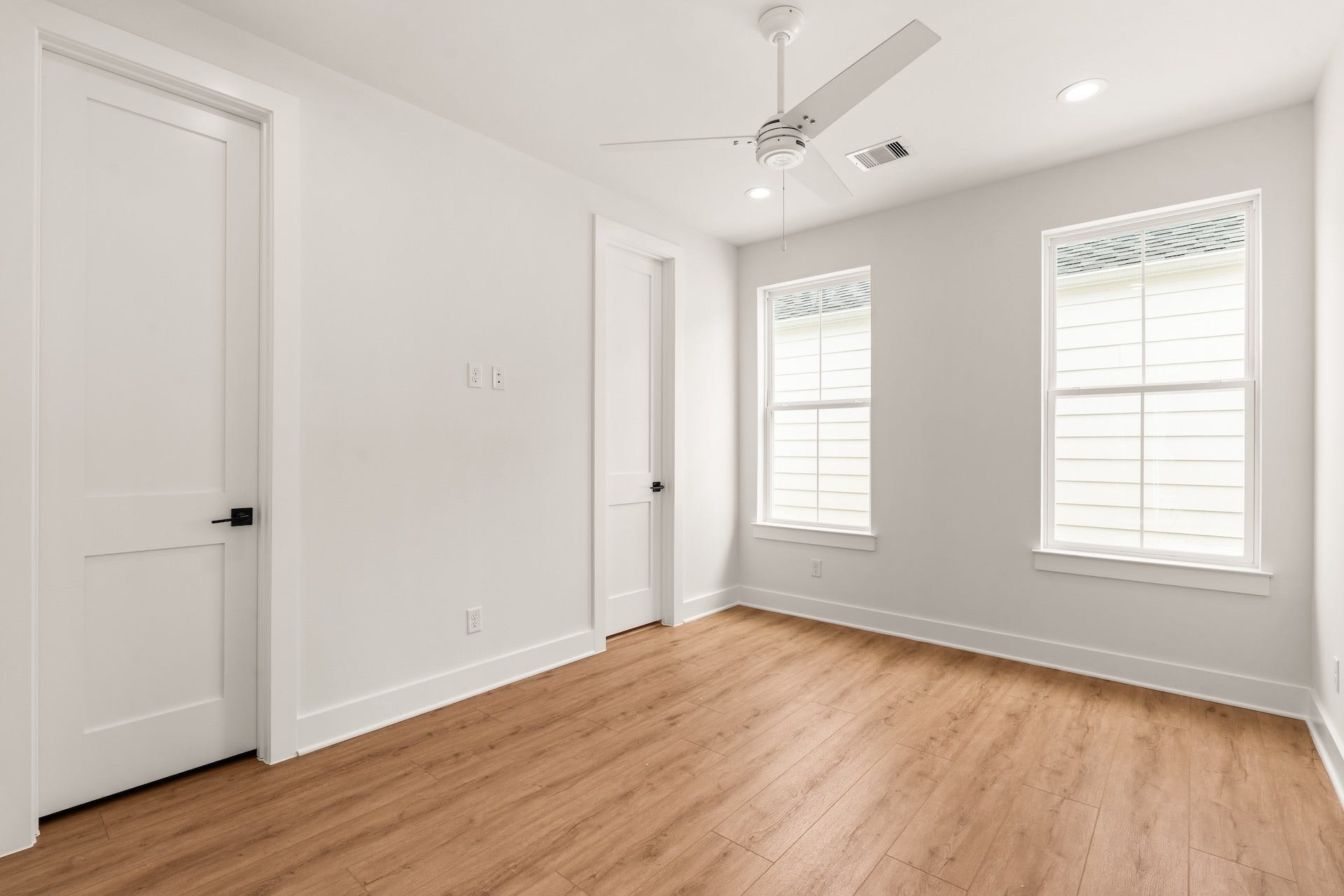 Bright secondary bedroom featuring warm wood-look flooring and sunlit views.