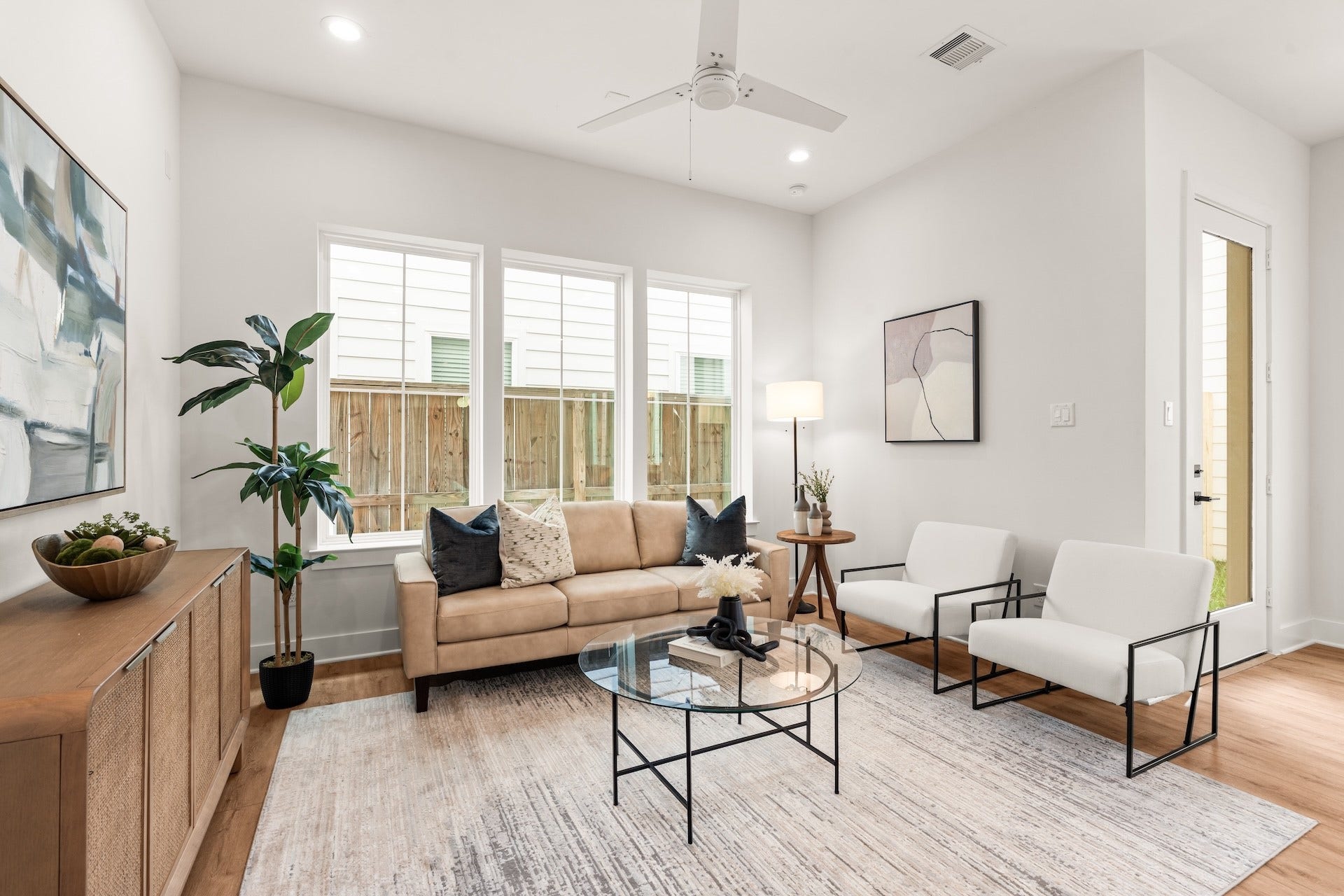 Bright living room framed by large windows, perfect for quiet relaxing or hosting guests.