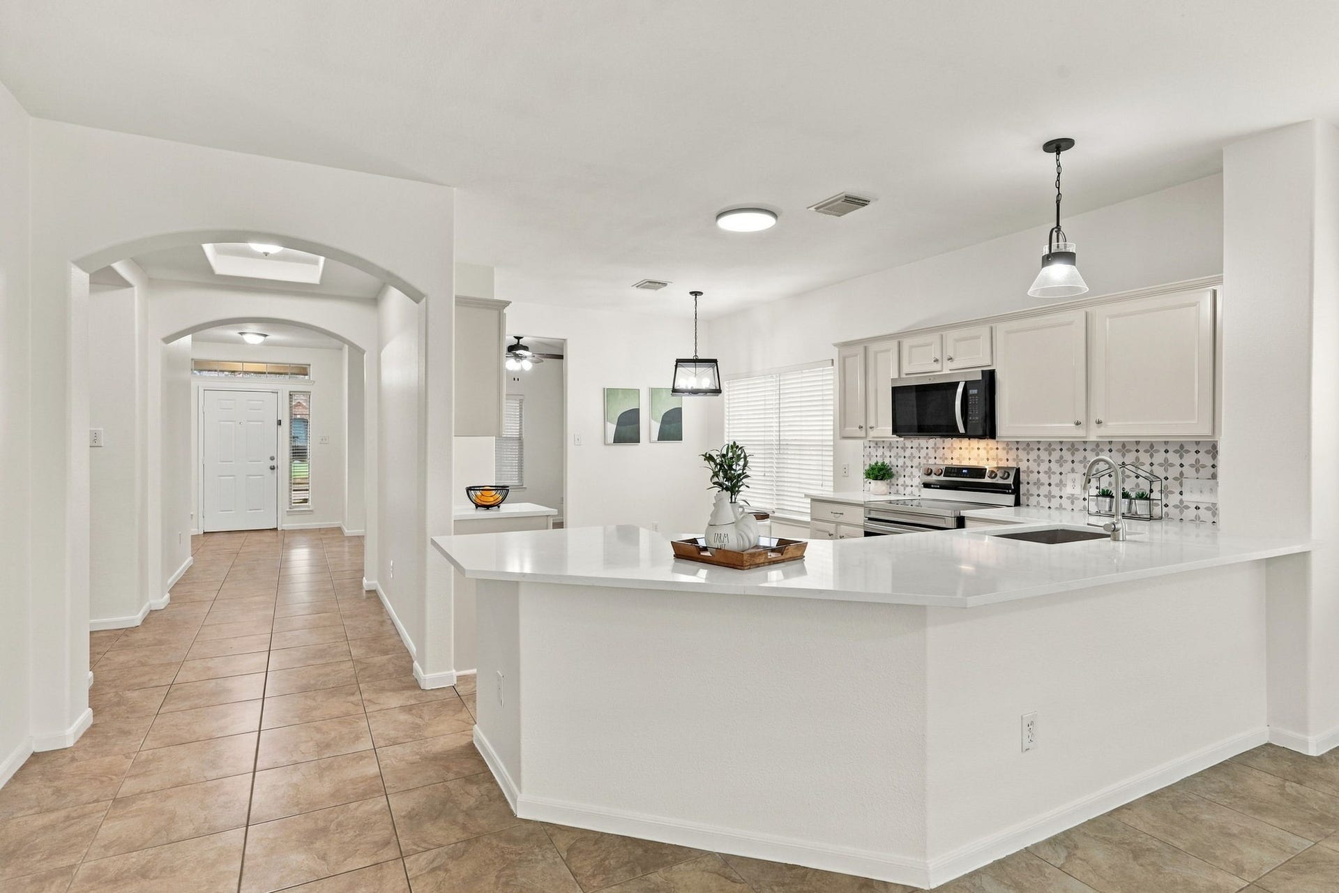 From another angle, the Kitchen showcases a spacious Breakfast Bar with Quartz countertops, providing additional seating for casual meals, morning coffee, or entertaining guests. Beautiful farmhouse-style pendant lights add a charming finishing touch above the bar.