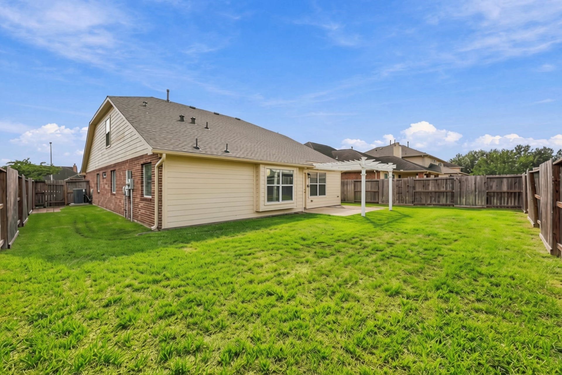 From the opposite side of the yard, this view highlights the additional side-yard space on both sides of the home, offering added flexibility for outdoor activities, gardening, storage, or future landscaping. The view also showcases the freshly painted exterior, enhancing the homes refreshed and well-maintained appearance.