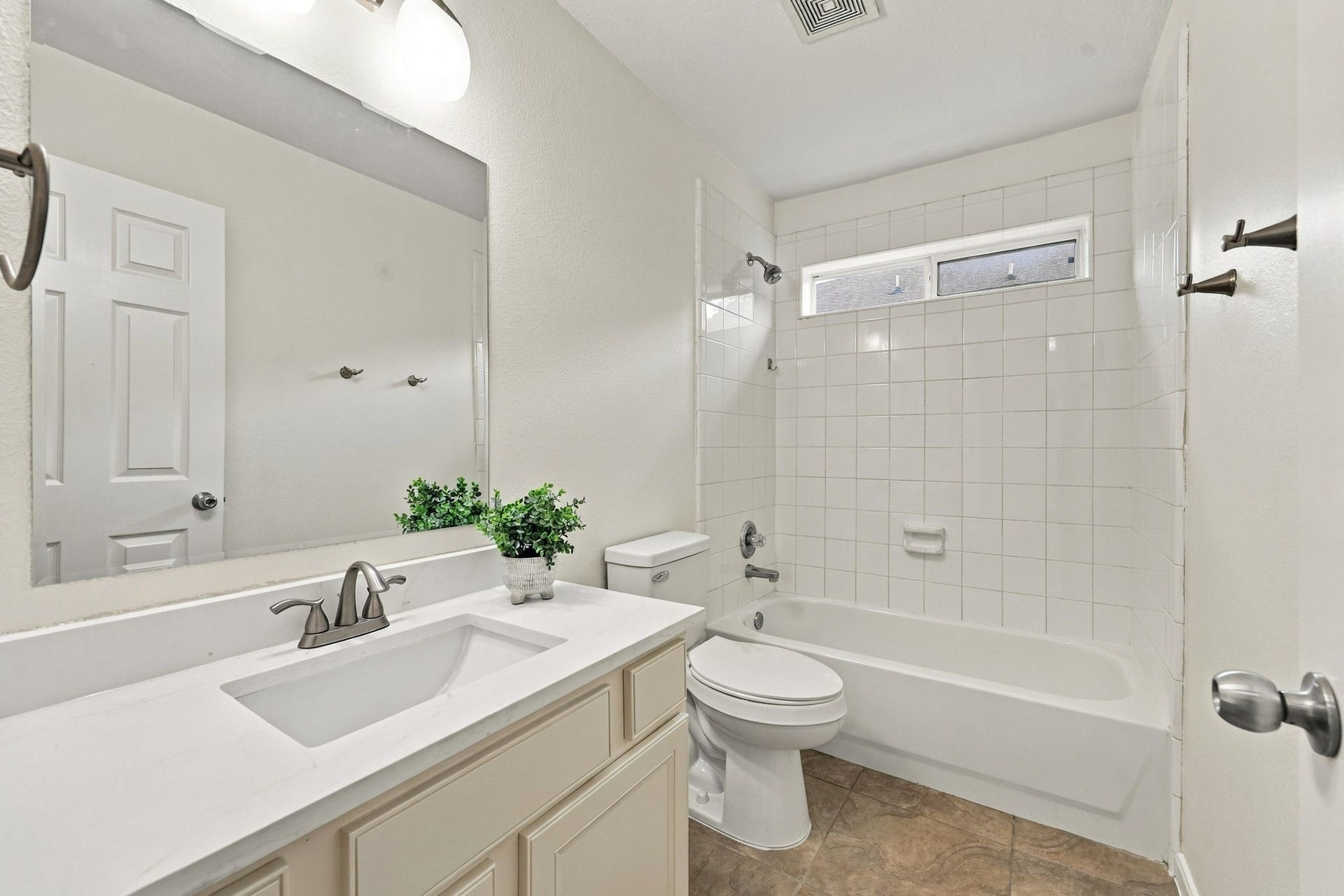 This Full Bath serves the Secondary Bedrooms on the first floor and has been thoughtfully updated with fresh paint on the walls and cabinetry, along with a tub and shower combination. Additional updates include newly installed Quartz countertops with a rectangular undermount sink, brushed nickel faucet, coordinating light fixture, and a new commode.