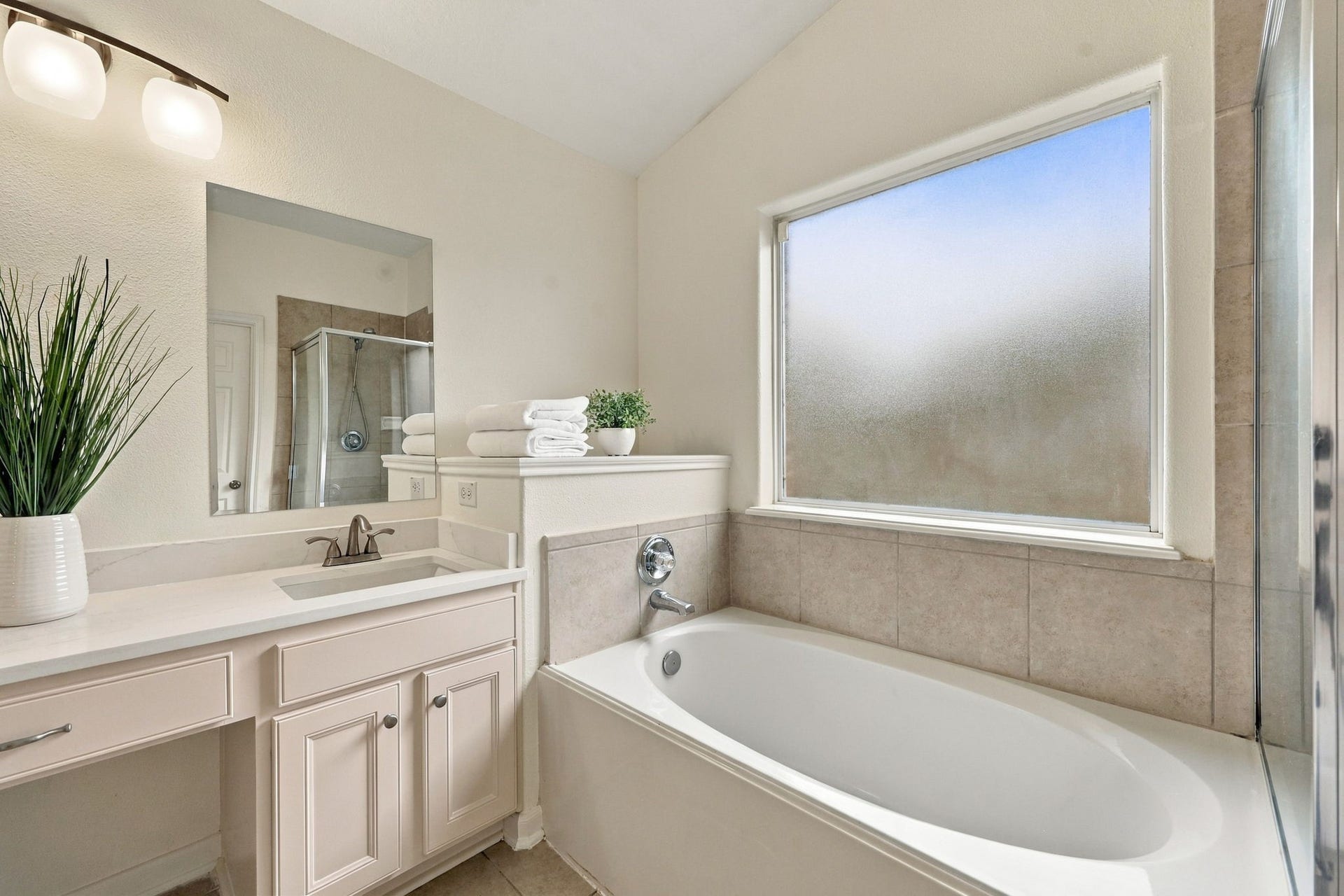 The large soaking tub is beautifully positioned beneath a privacy window, allowing natural light to fill the space while providing a relaxing setting to unwind and enjoy a peaceful bath.