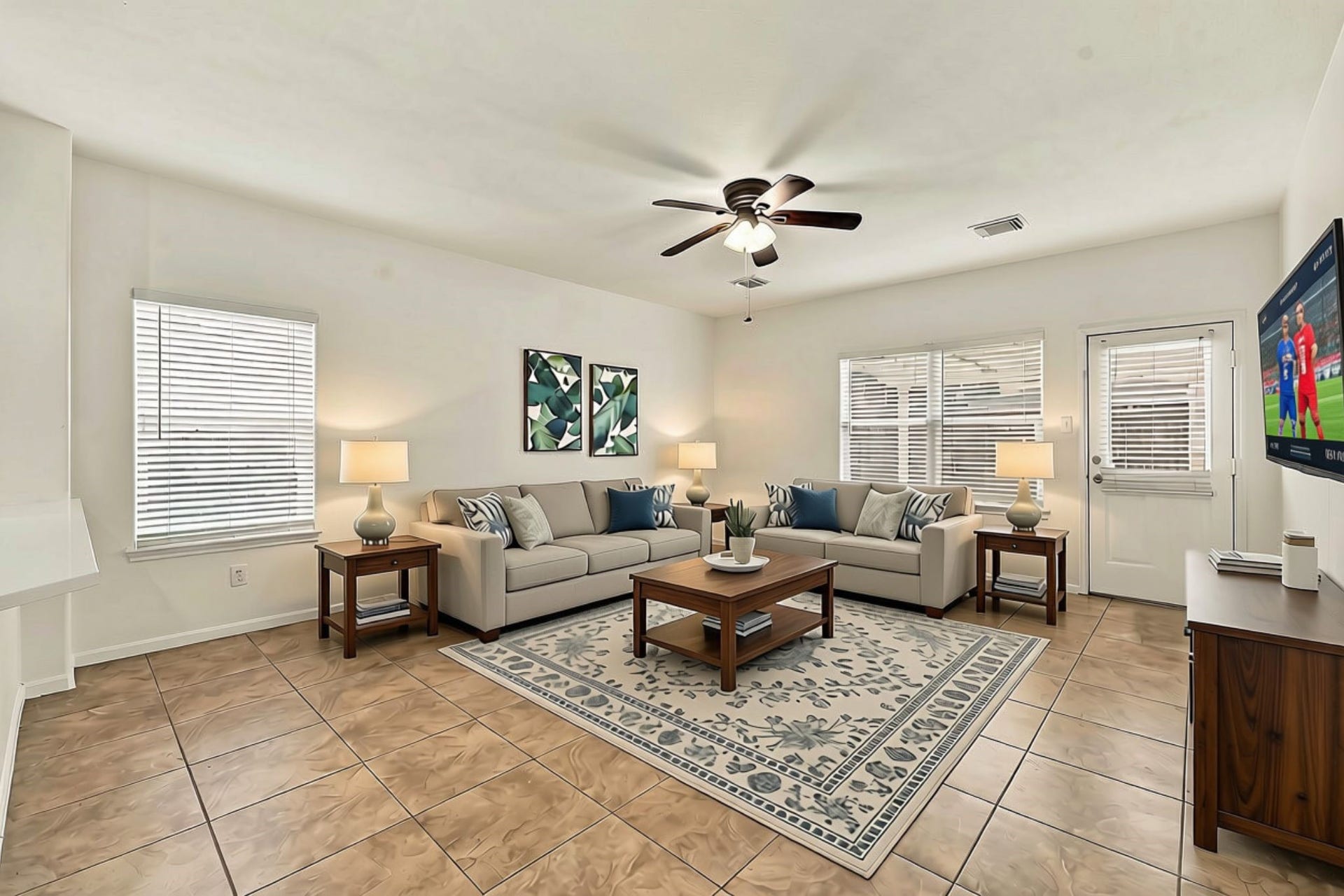 The spacious Family Room features neutral 18x18 tile flooring, abundant windows with 2-inch blinds, and fresh paint throughout. A door provides convenient access to the back Patio, while an oil-rubbed bronze five-blade ceiling fan adds comfort and style to the space. (Virtually staged)