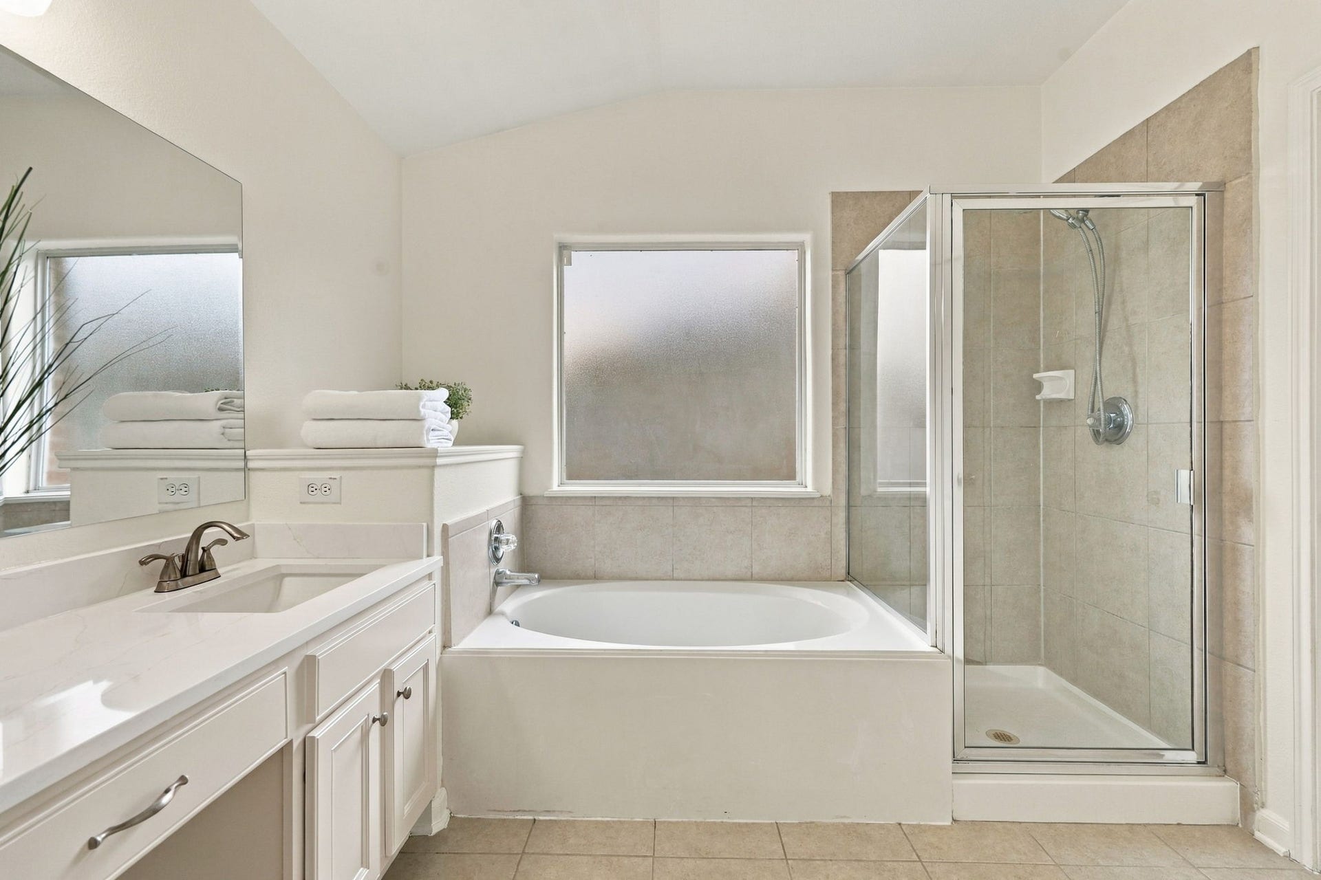This view showcases the entire Primary Bath, featuring fresh paint on the walls and cabinetry, along with Quartz countertops. The updated finishes create a bright, clean, and cohesive feel throughout the space.