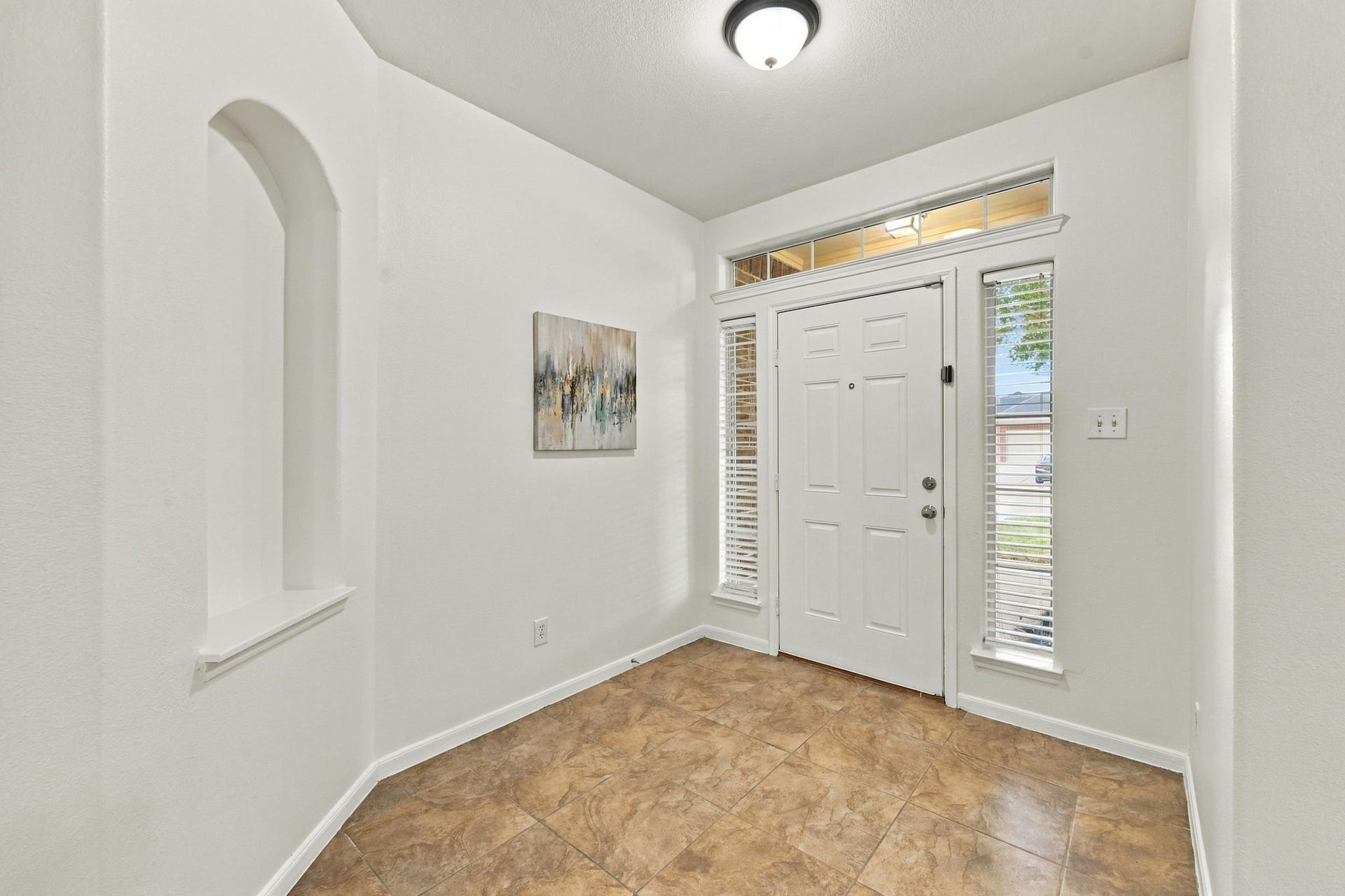 Looking back toward the front entrance and Foyer, the beautiful entry door is complemented by two side windows and an eye-level window above, allowing natural light to fill the space. An adjacent art niche provides the perfect spot to showcase your favorite artwork or dcor.