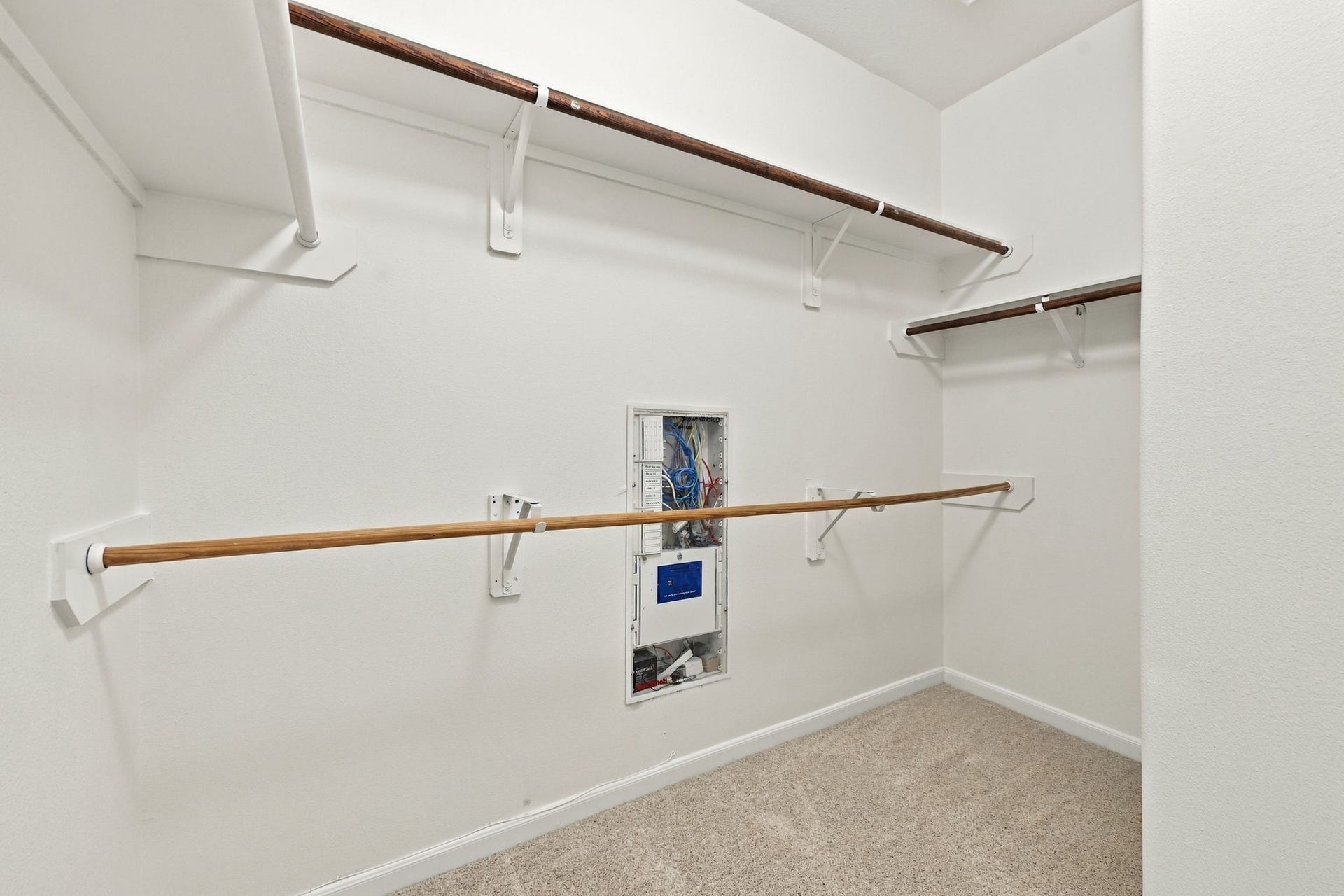 The spacious Primary Suite closet is large and offers multiple hanging bars and lots of storage to keep everything organized. A dedicated utility box provides convenient access for connecting internet service and other technology components throughout the home.
