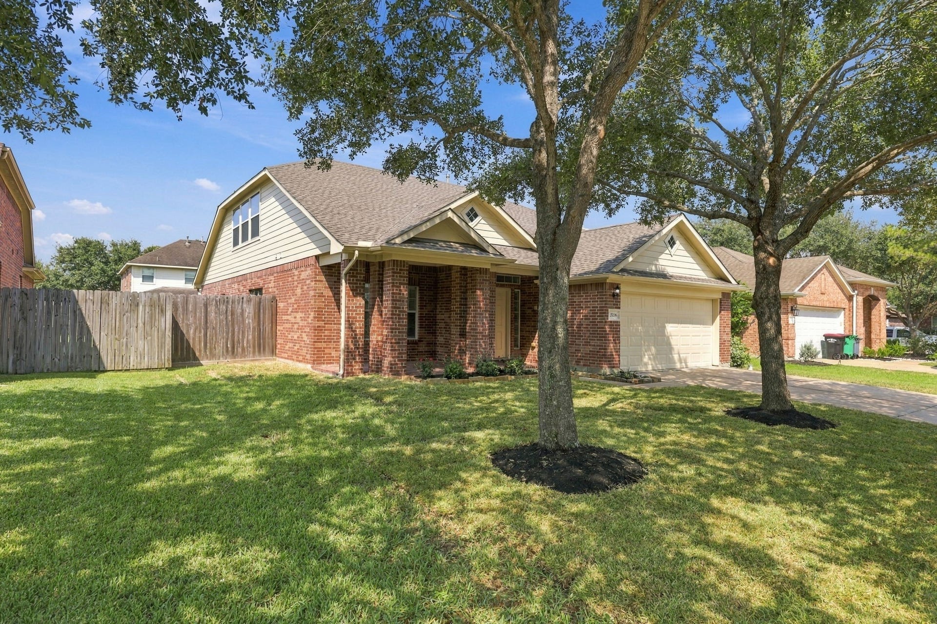 This home is nestled beneath a canopy of mature oak trees and features a charming gable roofline, a newly installed roof, and fresh exterior paint.