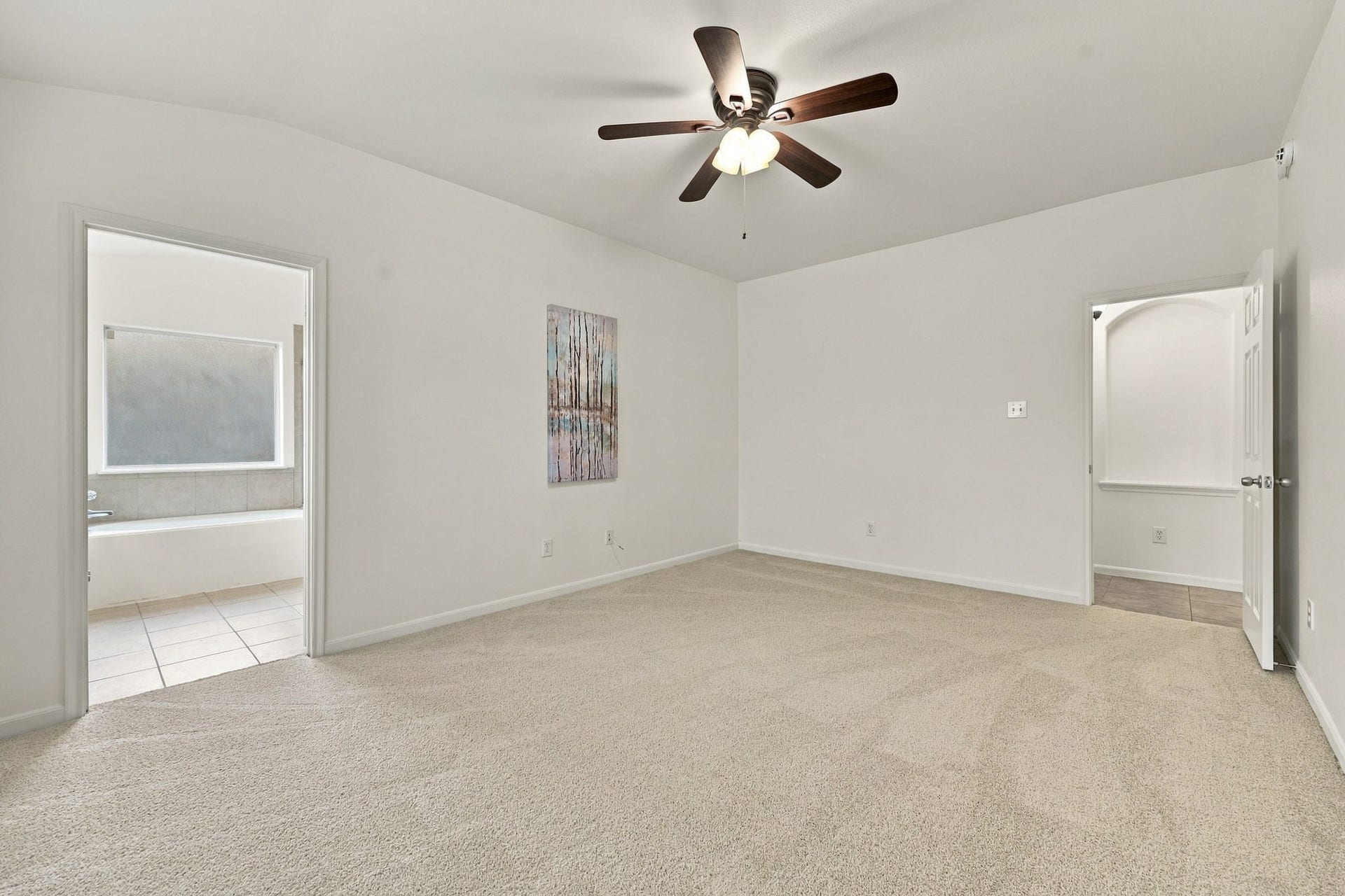 From the opposite side of the Primary Suite, you can see the entrance to the Primary Bath, along with ample wall space for additional furnishings, artwork, or a comfortable seating area.