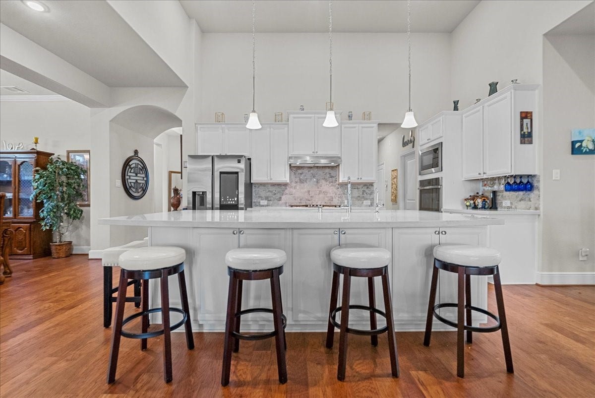 1714 Hartford Mills Lane, League City, TX 77573 Chef's eat-in island kitchen features 42" cabinets with crown molding, quartz countertops, and stainless steel appliances