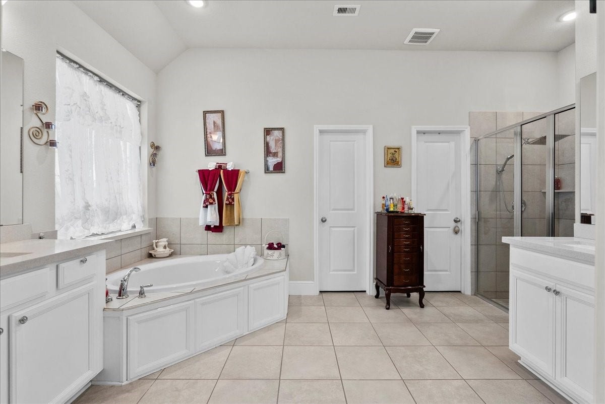 1714 Hartford Mills Lane, League City, TX 77573 The primary en-suite bath offers dual vanities, a walk-in shower, soaking tub and custom walk-in closet