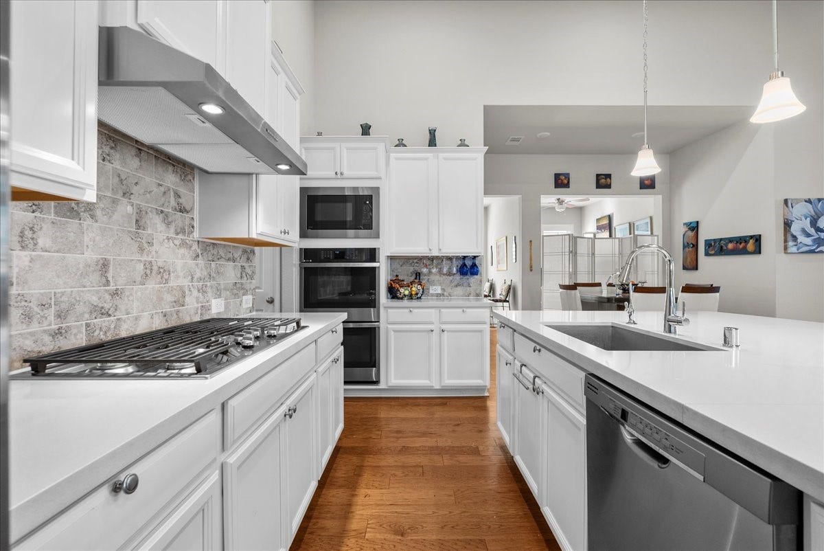 1714 Hartford Mills Lane, League City, TX 77573 Chef's eat-in island kitchen features 42" cabinets with crown molding, quartz countertops, and stainless steel appliances
