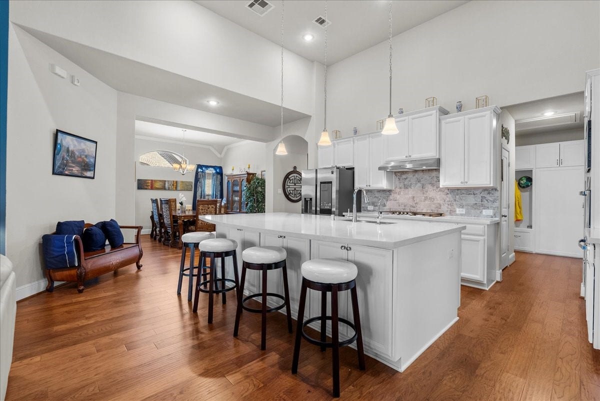 1714 Hartford Mills Lane, League City, TX 77573 Chef's eat-in island kitchen features 42" cabinets with crown molding, quartz countertops, and stainless steel appliances