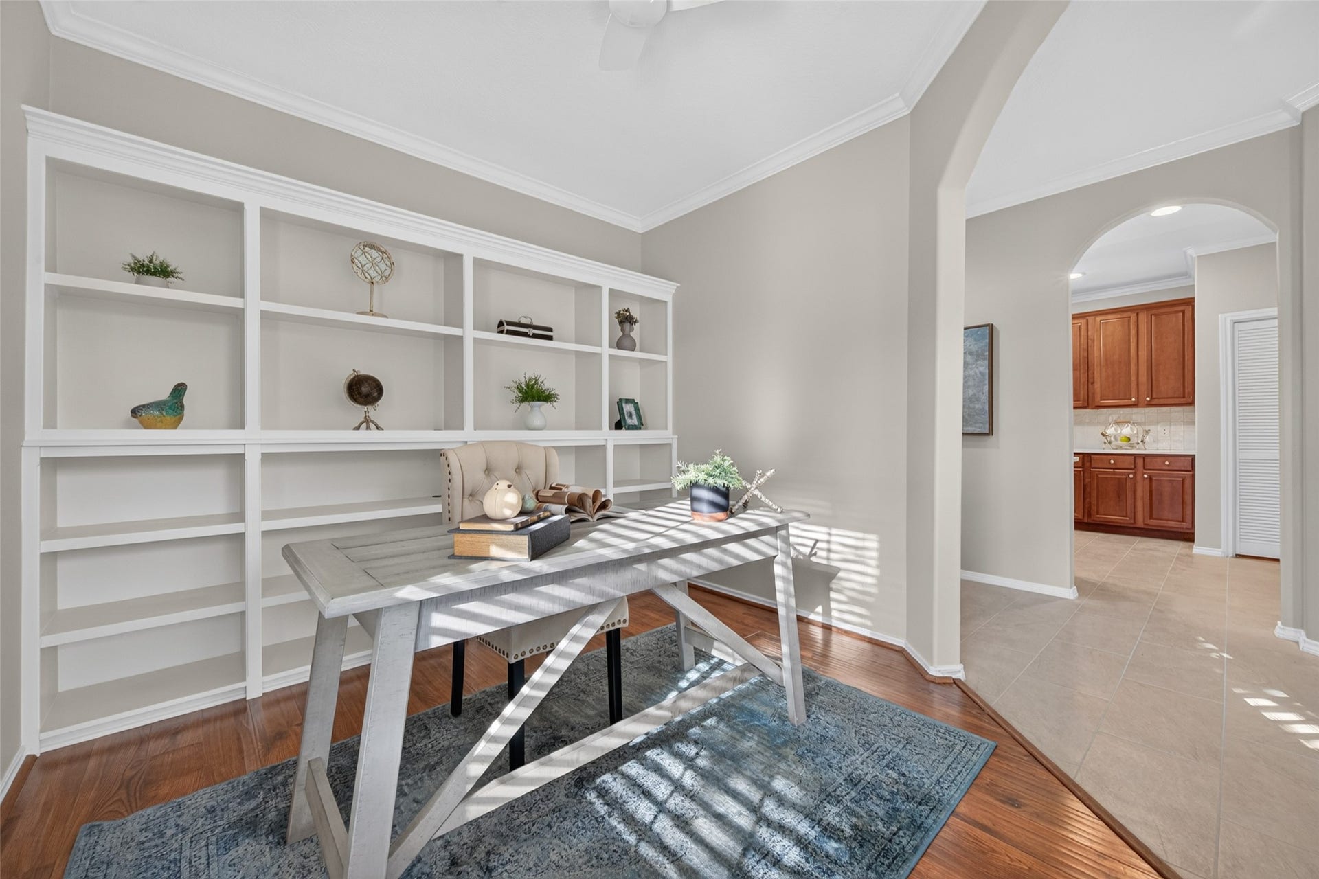 Another view of the home office highlights the custom built-in bookshelves, beautiful hardwood floors, and graceful archway connecting the space to the rest of the home.