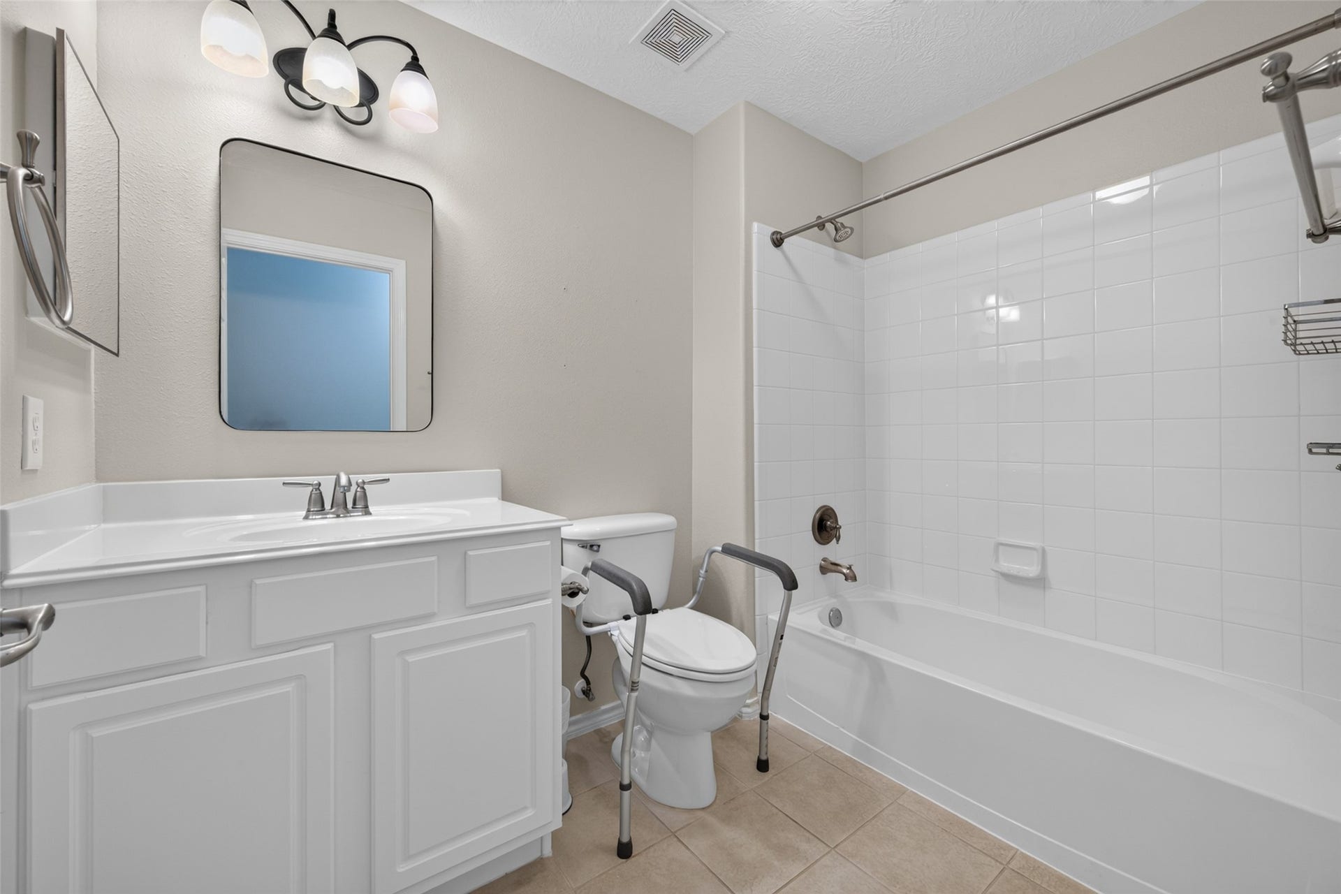 The secondary bathroom features a white vanity with cabinet storage, tile flooring, and a tub-and-shower combination with a white tile surround.
