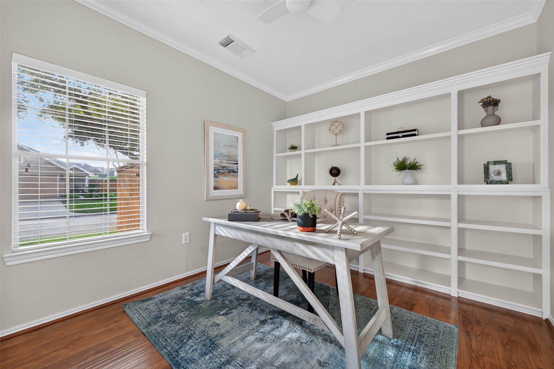 Just off the entryway, this inviting home office features beautiful hardwood floors, crown molding, custom built-in bookshelves, and a large window overlooking the front yard.