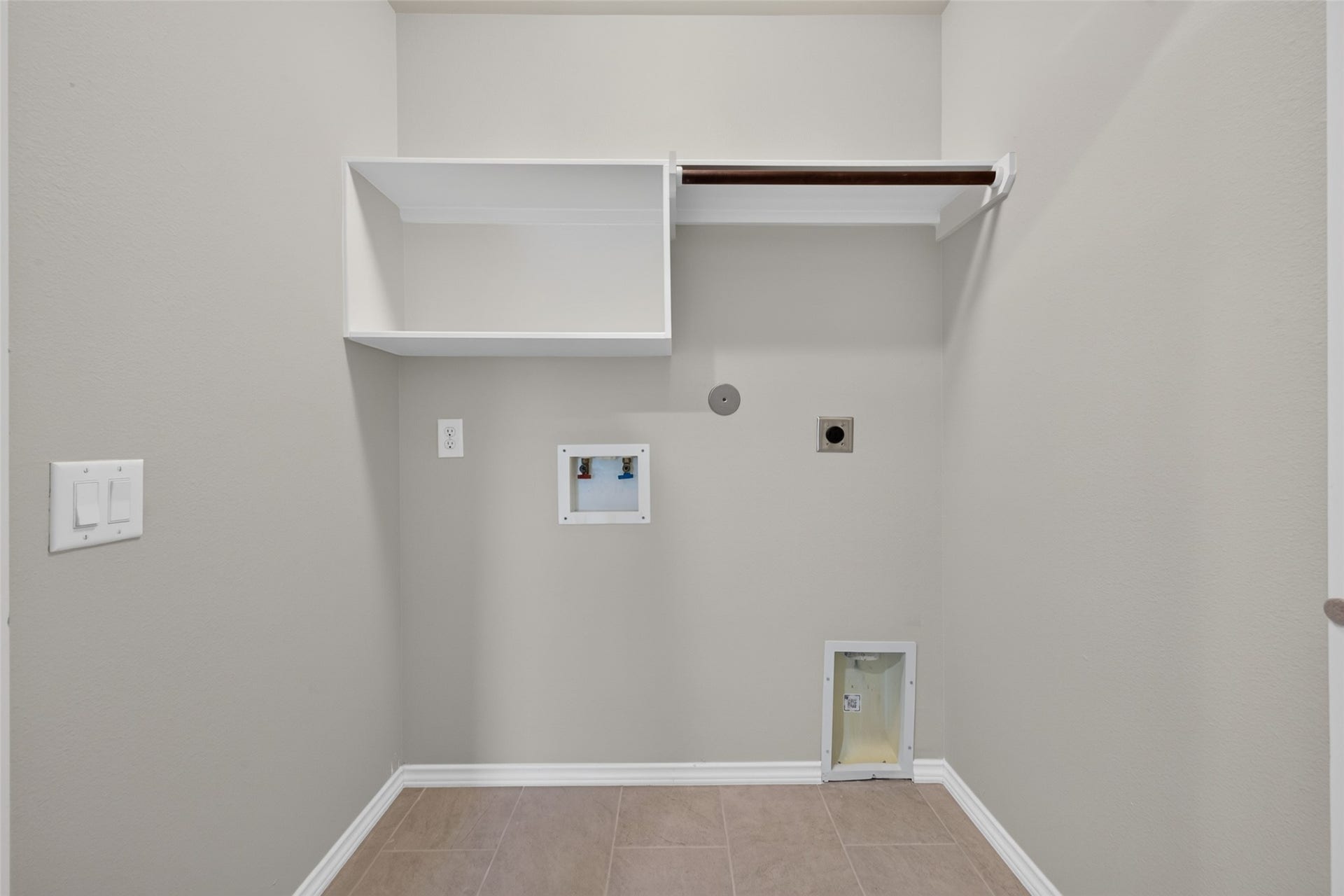 Convenient utility room with washer and dryer connections, new tile flooring, fresh paint and overhead shelving for additional storage.