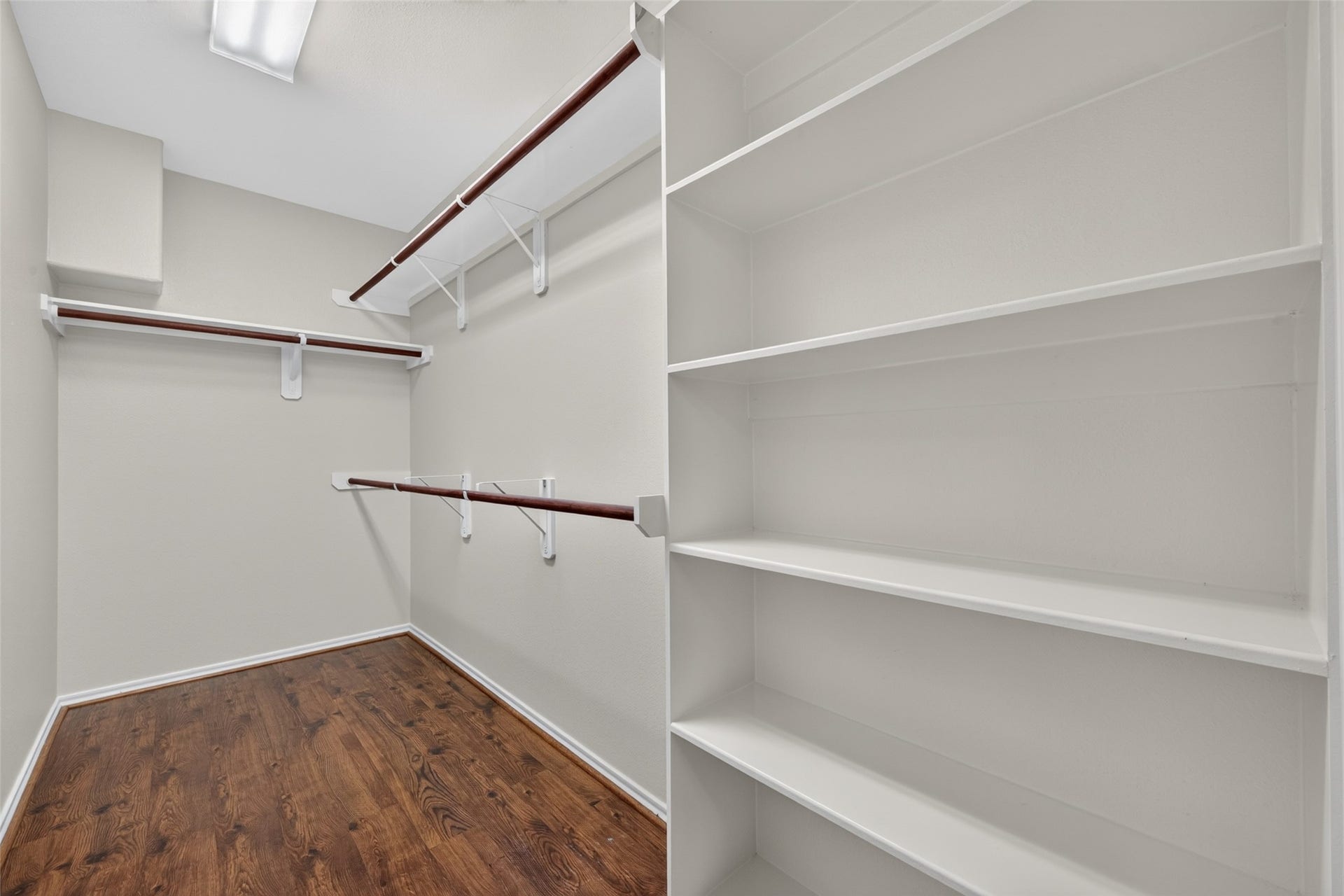 The walk-in closet in the primary bedroom offers plenty of room for clothing and accessories, featuring multiple hanging rods and built-in shelving.