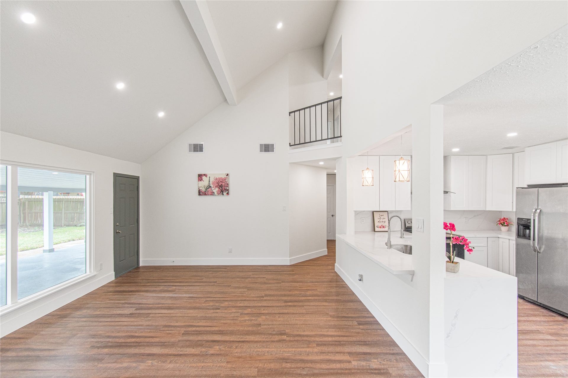 13130 Kingsmill Drive, Houston, TX 77478 Expansive and filled with light, this open-concept living area showcases high vaulted ceilings and elegant hardwood floors, while the modern kitchen dazzles with sleek countertops and stainless steel appliances, seamlessly blending style and function.