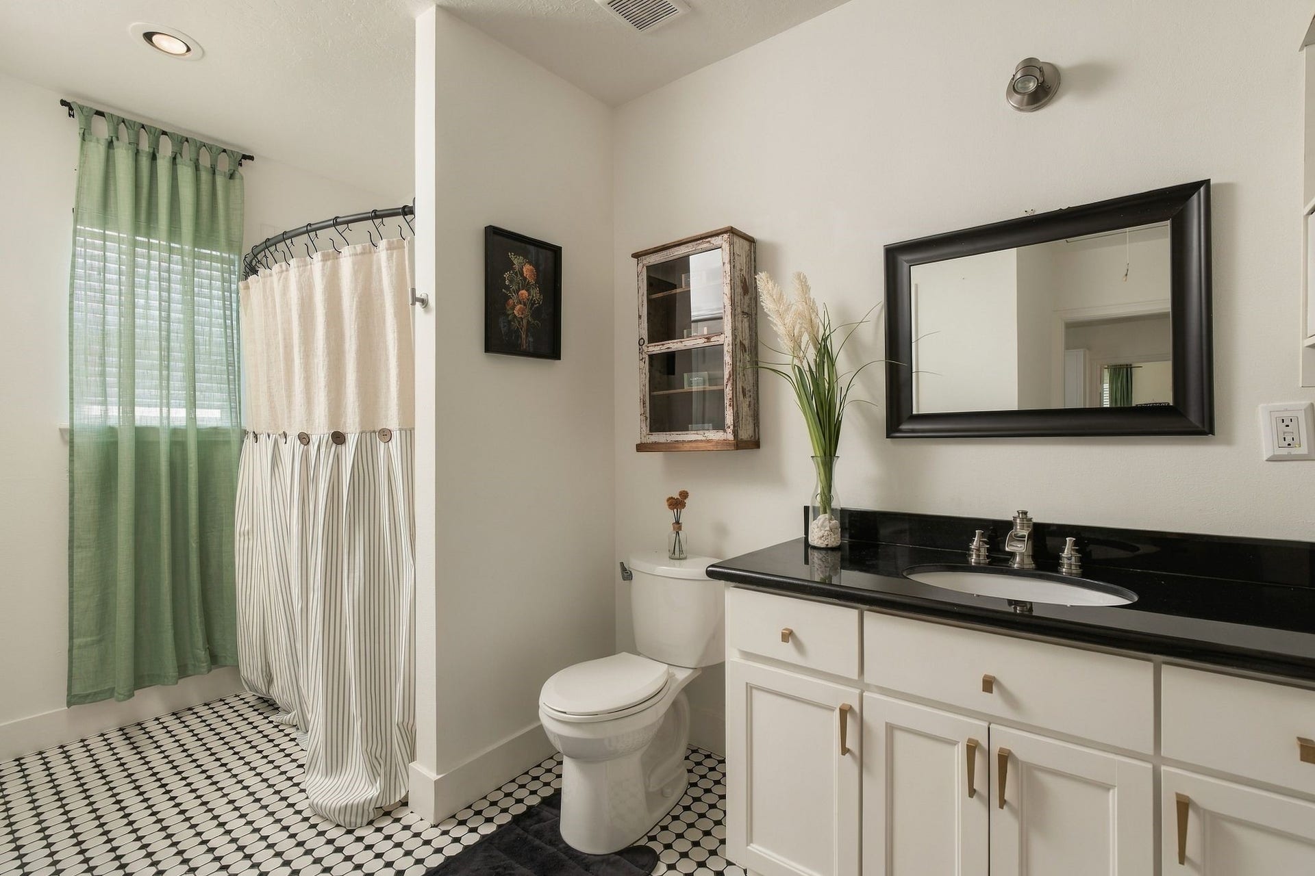 614 Coronado Street, Houston, TX 77009 Full secondary bathroom with tub-shower combination, vanity storage, and a dedicated utility closet accommodating a full-size washer and dryer, plus additional storage. A practical feature in this historic bungalow.