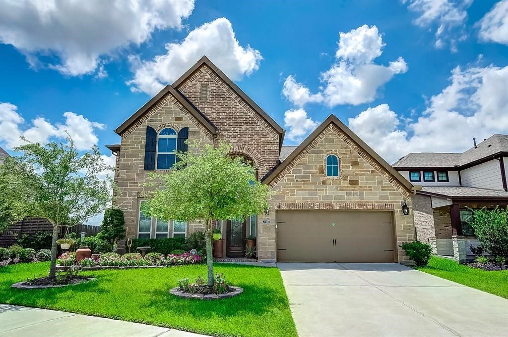 27107 Naples Run Lane, Katy, TX 77494 Charming two-story home with a beautiful stone and brick exterior, complete with a spacious driveway and attached garage.