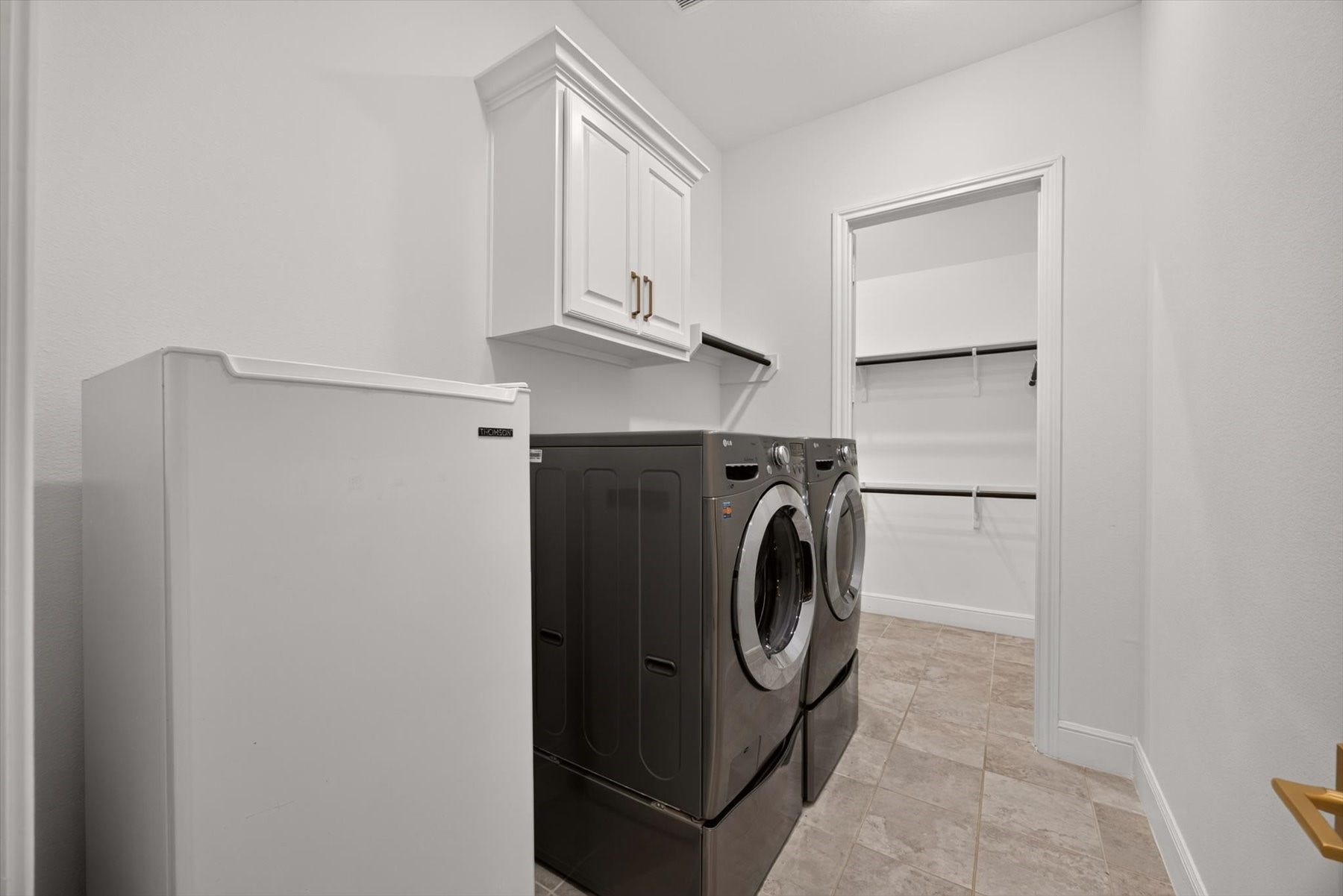 1219 Mcmurtry Ridge Drive, Katy, TX 77494 Convenient laundry room with washer and dryer, built-in cabinetry, and direct access to the spacious primary closet.